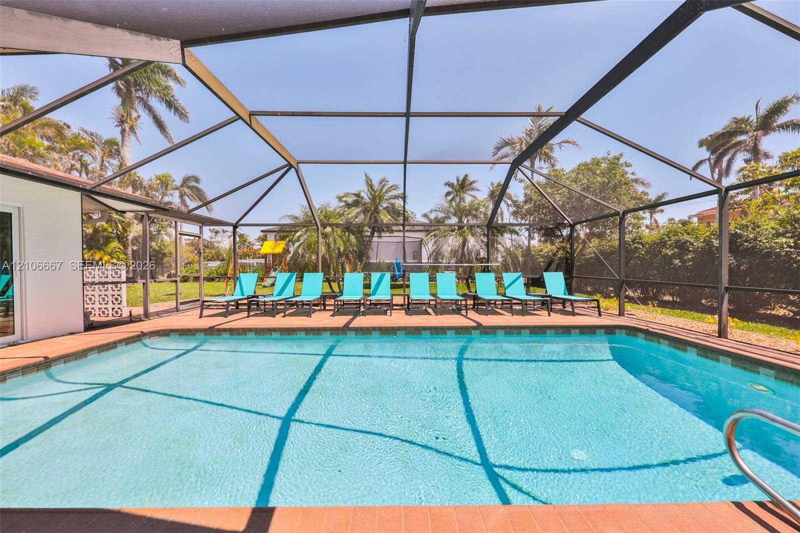 209 Bayshore Drive, Cape Coral, FL 33904 Screen-enclosed swimming pool featuring a paved pool deck and metal frame structure