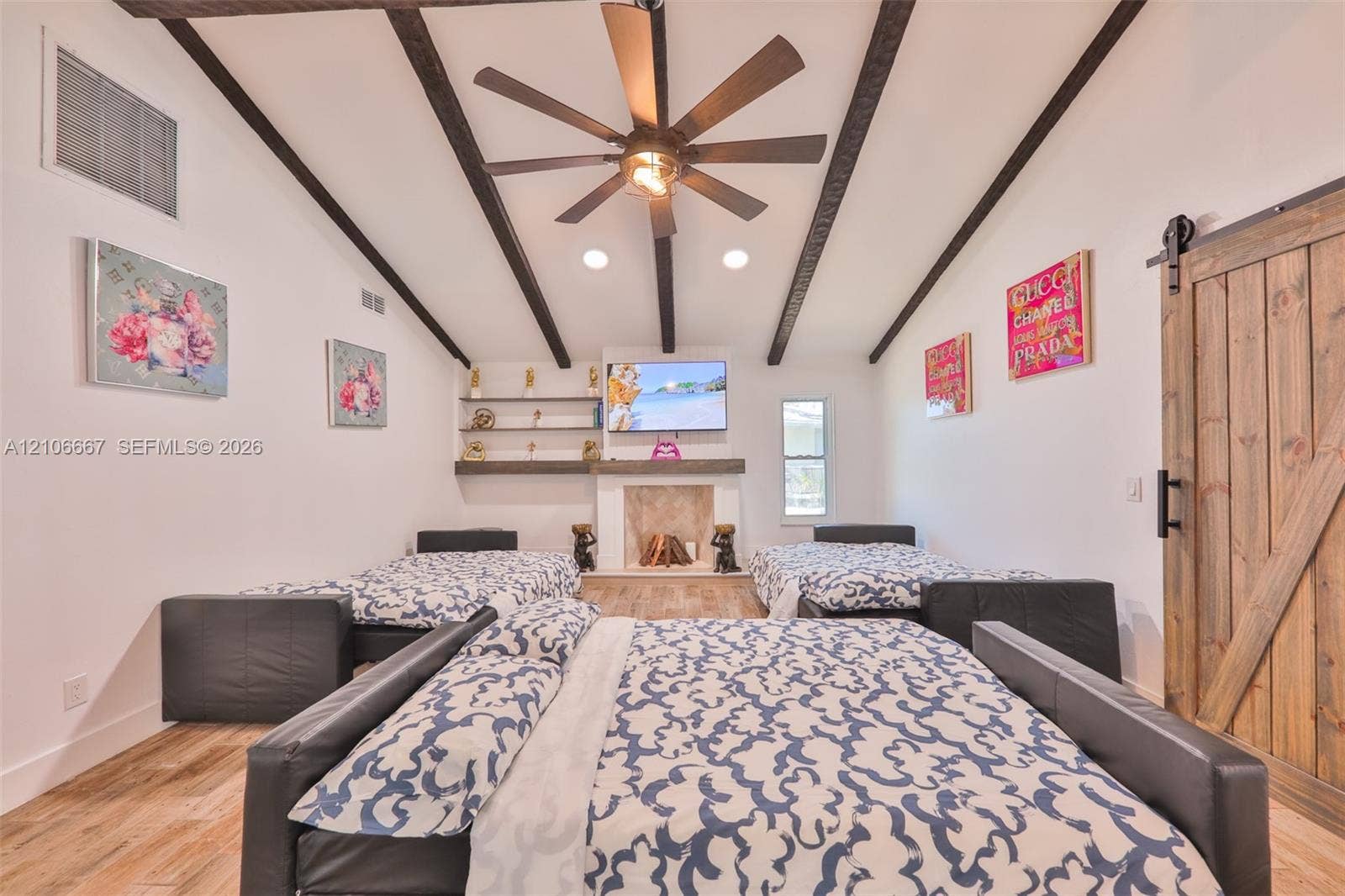 209 Bayshore Drive, Cape Coral, FL 33904 Vaulted ceiling with exposed decorative beams, wood-finish flooring, fireplace with stone-surround and mantle, built-in shelving, and sliding barn door
