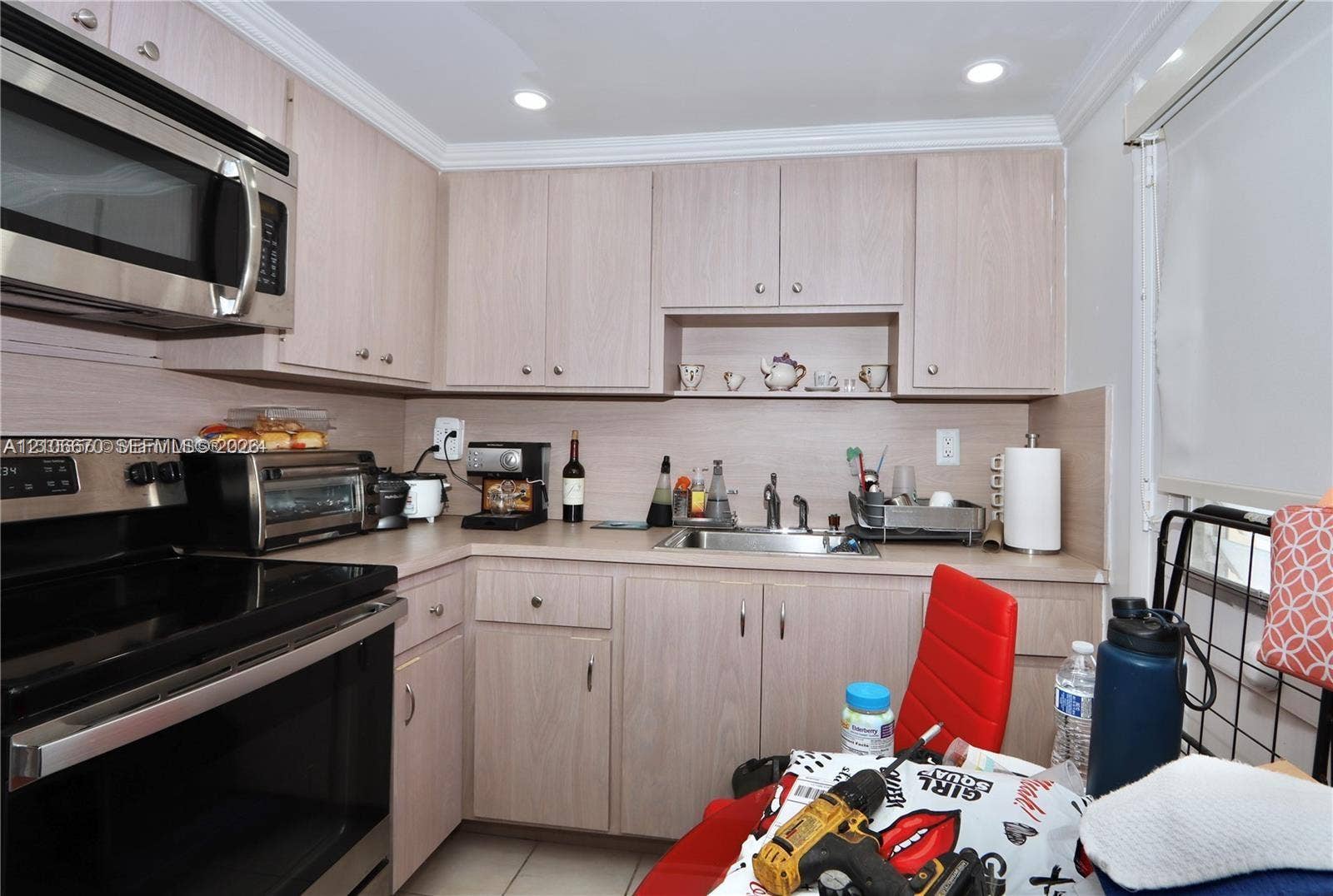 3030 Marcos Drive, #T512, Aventura, FL 33160 Kitchen featuring light-finish cabinetry, stainless steel microwave, integrated oven, and a metal sink with a high-arch faucet