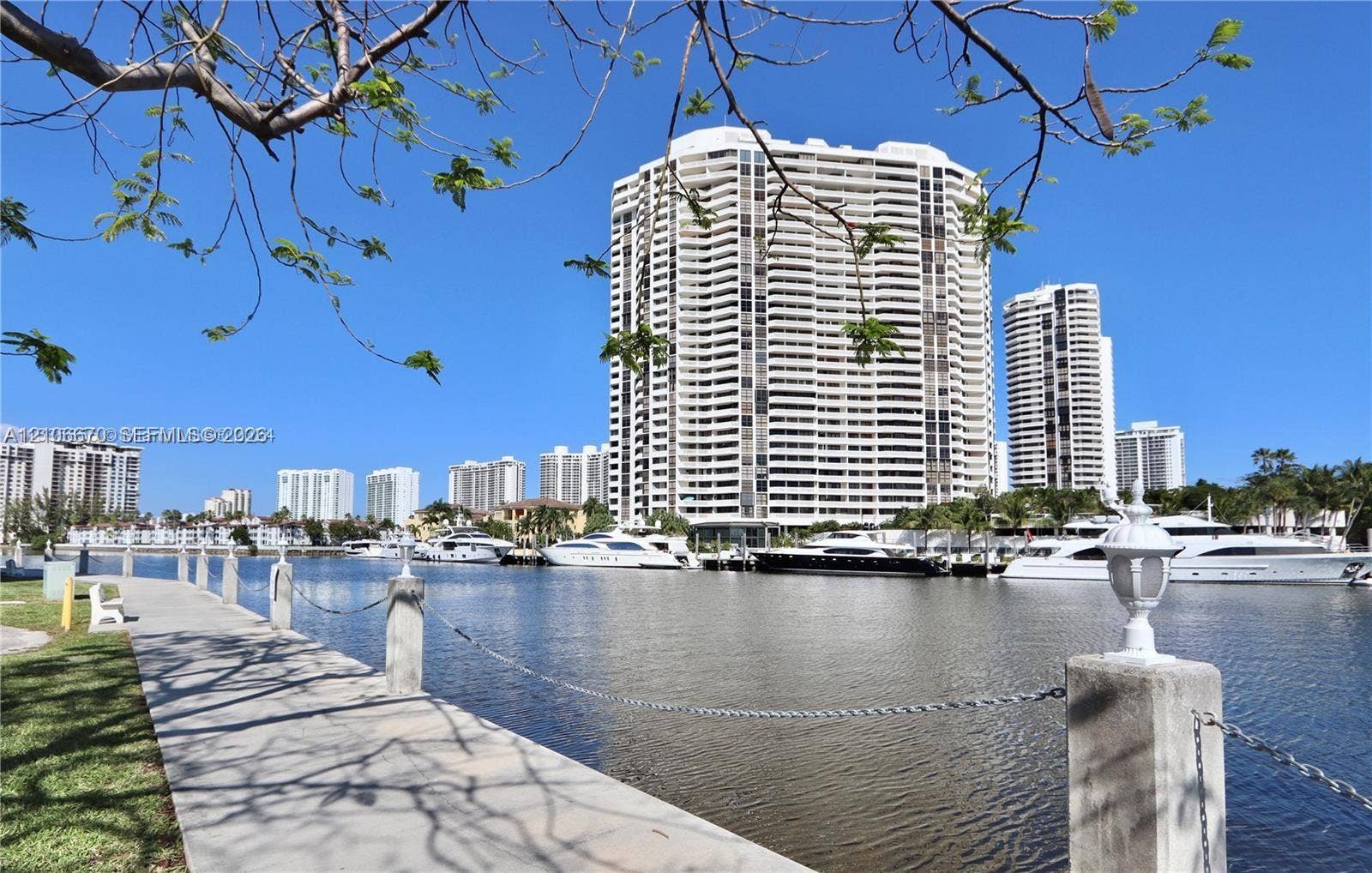 3030 Marcos Drive, #T512, Aventura, FL 33160 Waterfront walkway featuring concrete pavers, stone-capped bollards with chain link, and integrated post-top lighting