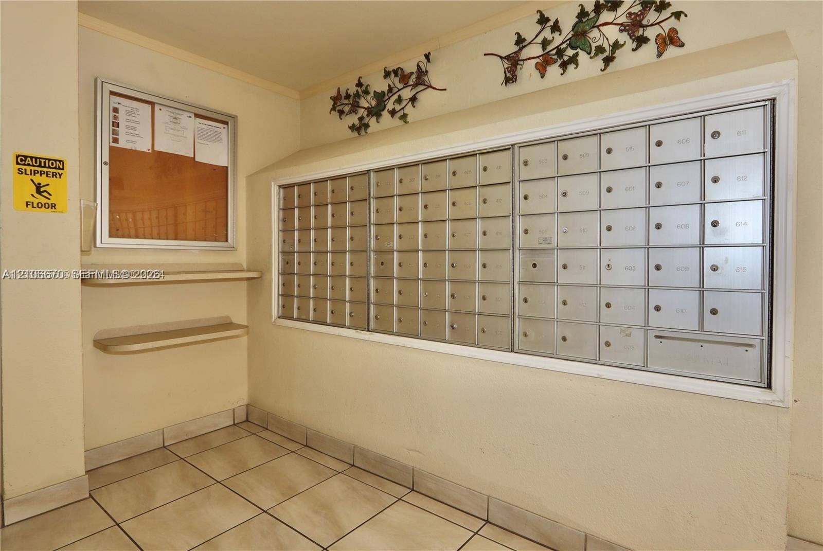 3030 Marcos Drive, #T512, Aventura, FL 33160 Wall-mounted metal mail distribution center, integrated bulletin board, and two recessed utility shelves with tile flooring