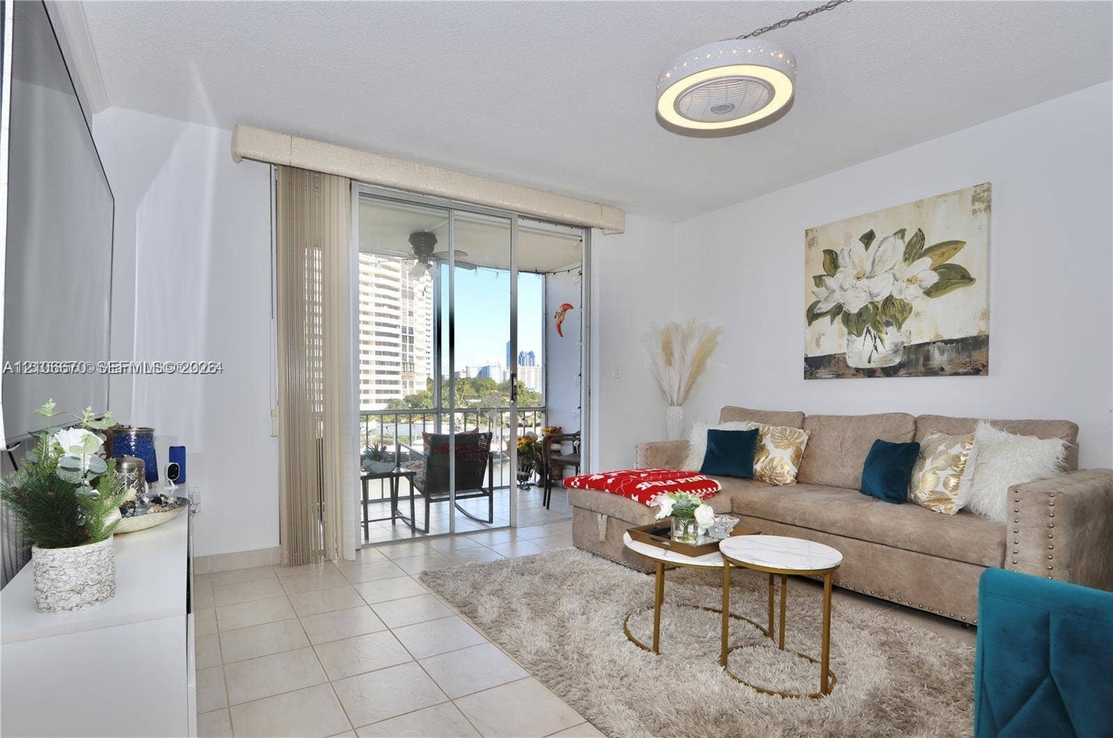 3030 Marcos Drive, #T512, Aventura, FL 33160 Living area featuring large-format ceramic tile flooring, a circular recessed LED ceiling light fixture, and sliding glass doors with vertical blinds