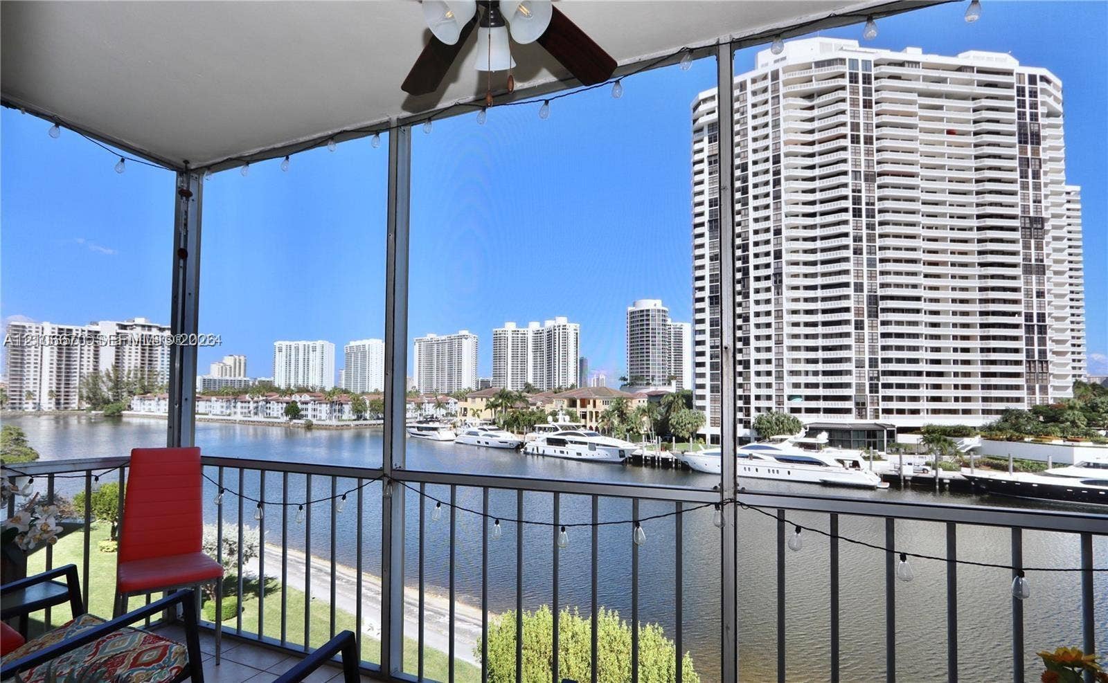 3030 Marcos Drive, #T512, Aventura, FL 33160 Screened-in balcony featuring a metal railing, overhead ceiling fan, and string lighting