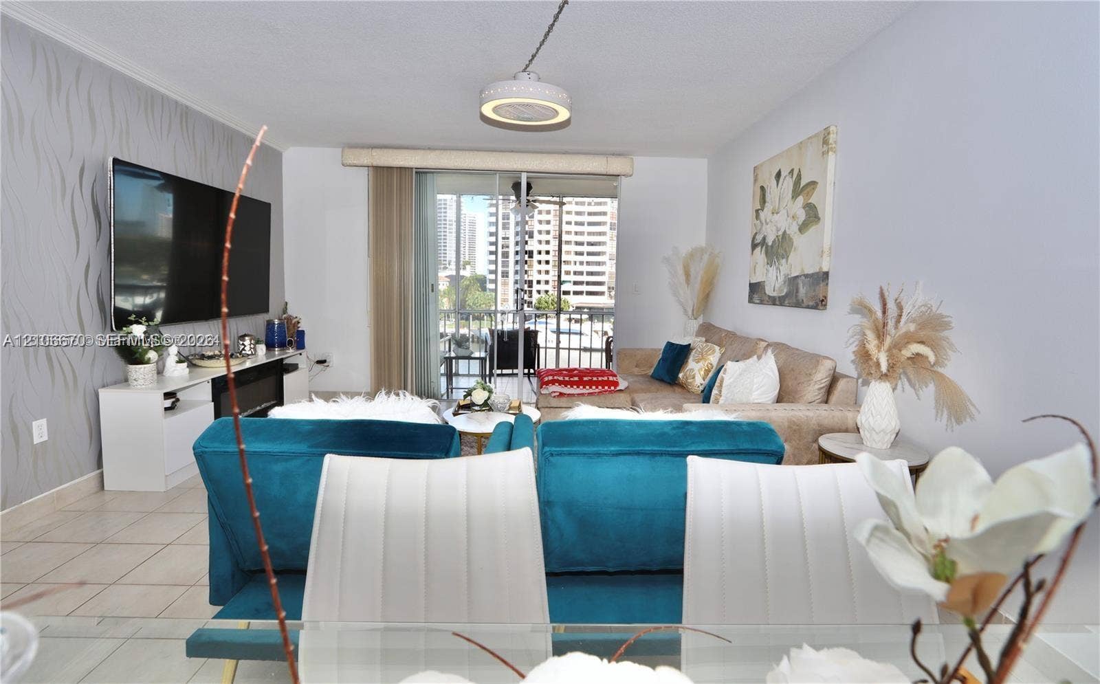3030 Marcos Drive, #T512, Aventura, FL 33160 Living area featuring tile flooring, textured accent wall, integrated electric fireplace, and sliding glass door access to a balcony