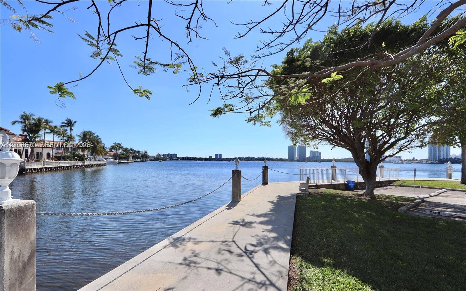 3030 Marcos Drive, #T512, Aventura, FL 33160 Waterfront concrete bulkhead, paved walkway, metal chain railing, and mature shade tree