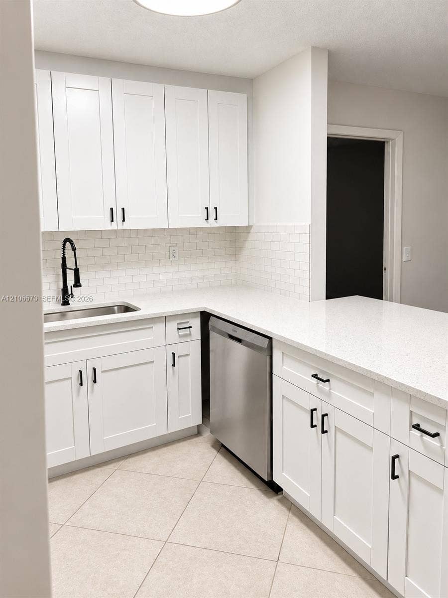 704 SE 2nd Avenue, #440, Deerfield Beach, Deerfield Beach, FL 33441 White shaker-style cabinetry with matte black hardware, stone-composite countertops, subway tile backsplash, stainless steel dishwasher, and undermount kitchen sink with a high-arch pull-down faucet