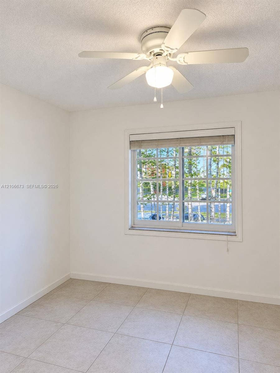 704 SE 2nd Avenue, #440, Deerfield Beach, Deerfield Beach, FL 33441 Large-format ceramic tile flooring, ceiling fan with integrated light fixture, and window with white muntin detailing