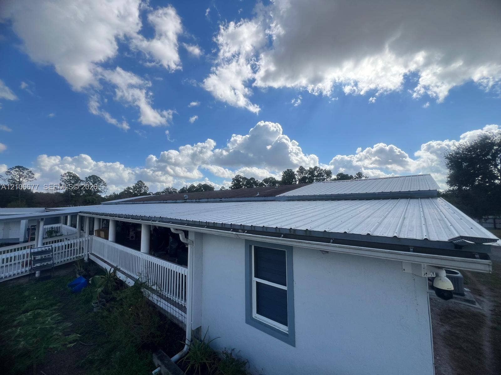 Exterior featuring a white metal roof, a full-length covered porch with a white railing, and exterior white siding