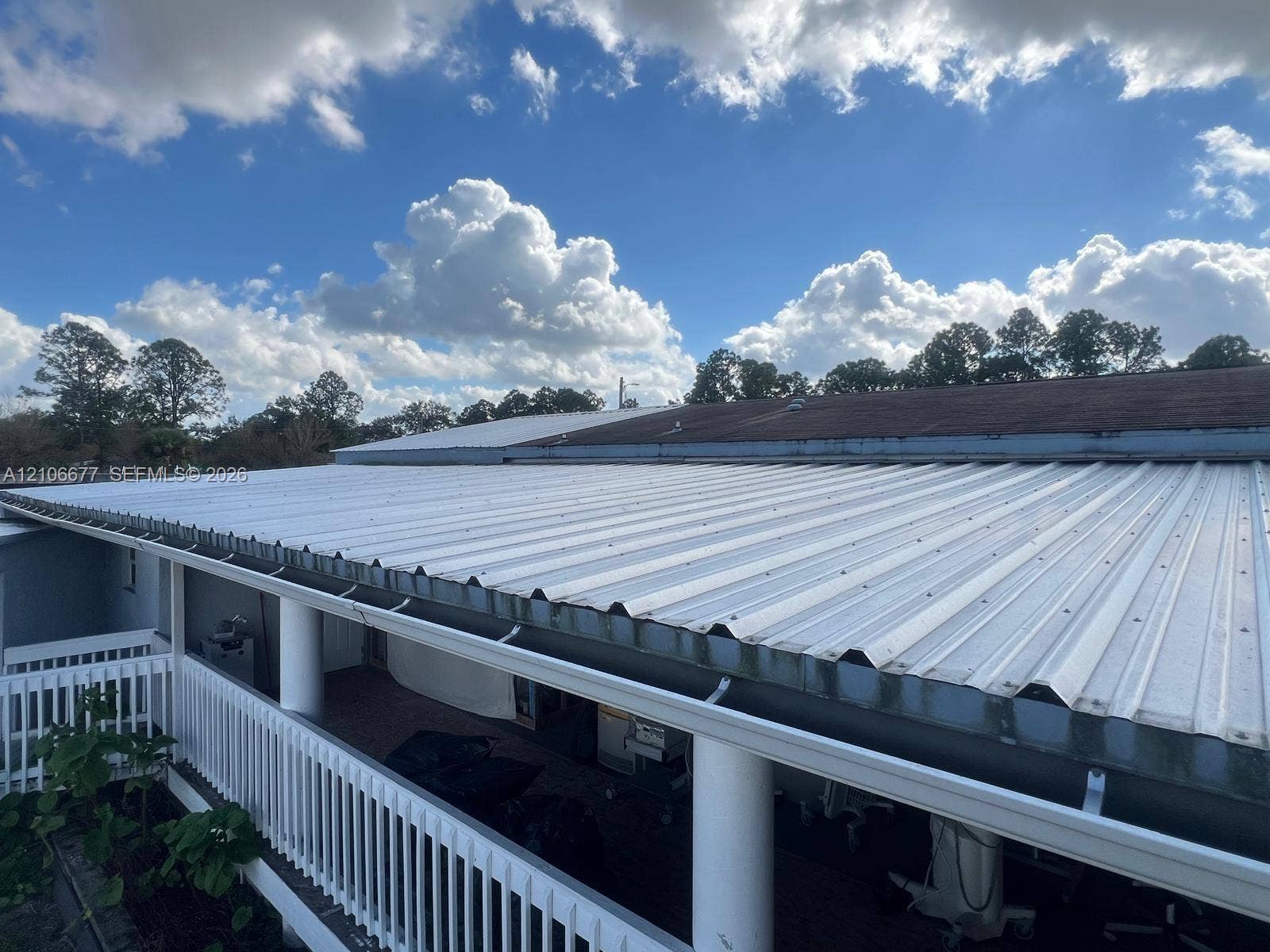 Corrugated metal roofing featuring a white finish, integrated gutter system, and structural support columns with a white railing
