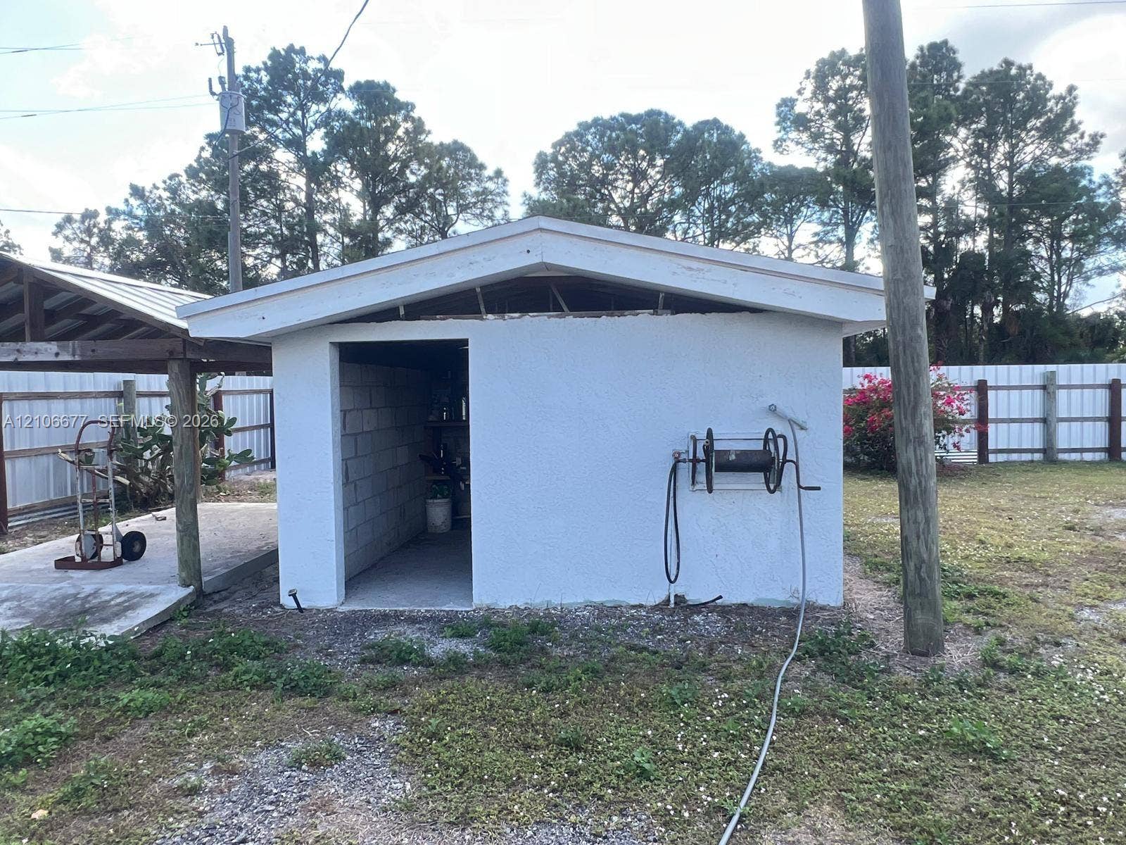 Detached structure with stucco exterior, concrete block construction, and wall-mounted hose reel
