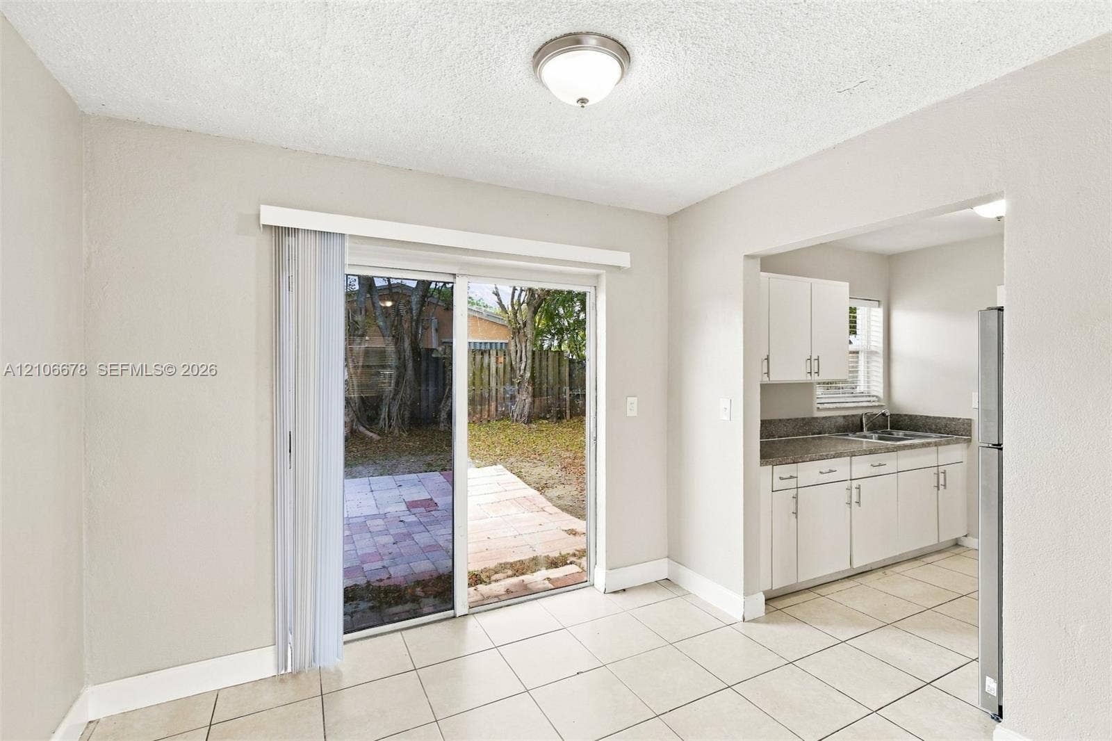 7060 Hood Street, Hollywood, Hollywood, FL 33024 Tile flooring throughout, sliding glass door, white cabinetry, stone-surface countertops, and exterior brick patio