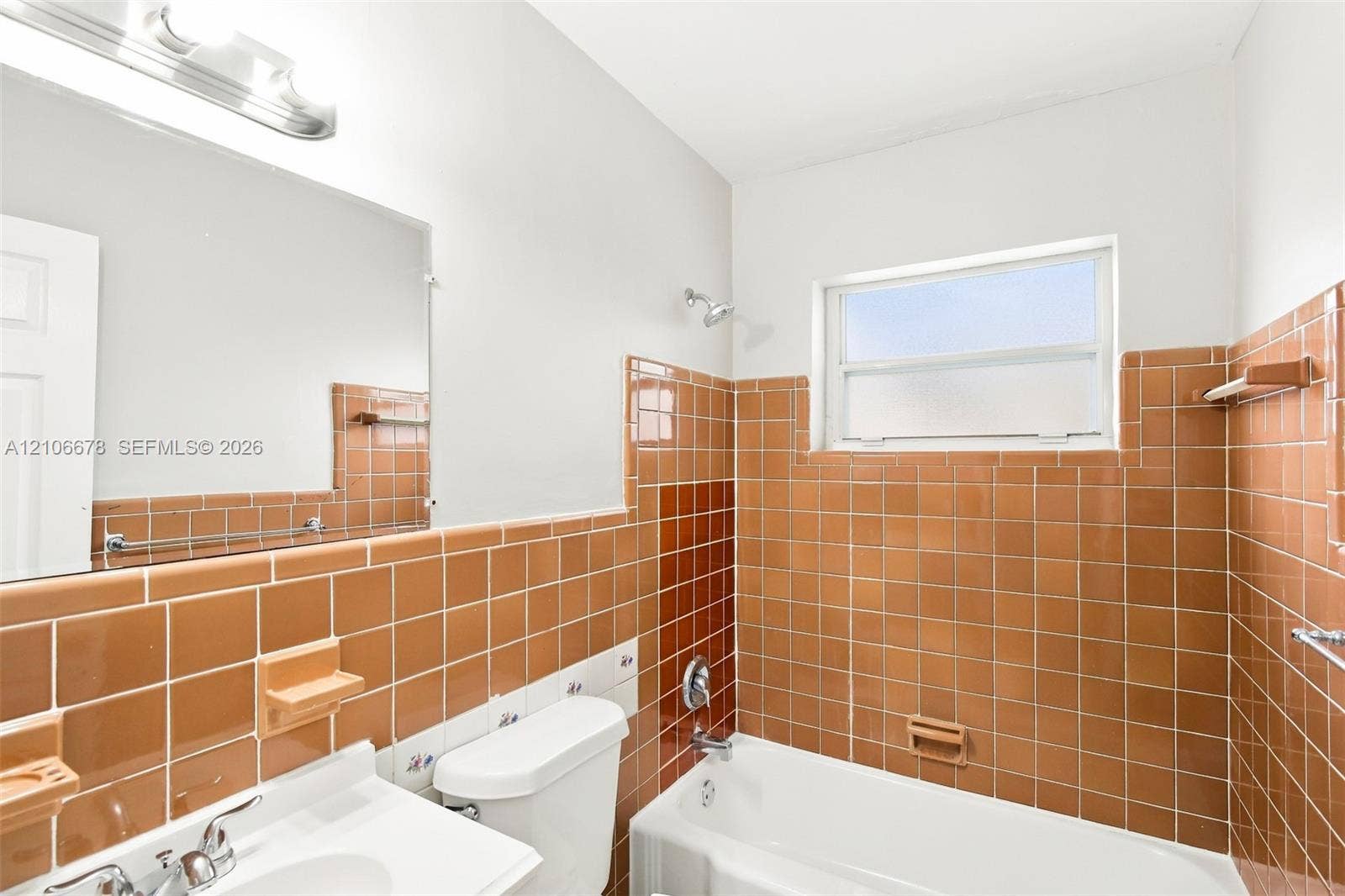 7060 Hood Street, Hollywood, Hollywood, FL 33024 Bathroom featuring square ceramic wall tiling, a built-in bathtub with shower head, a white vanity with integrated basin, a large frameless mirror, and a wall-mounted light fixture