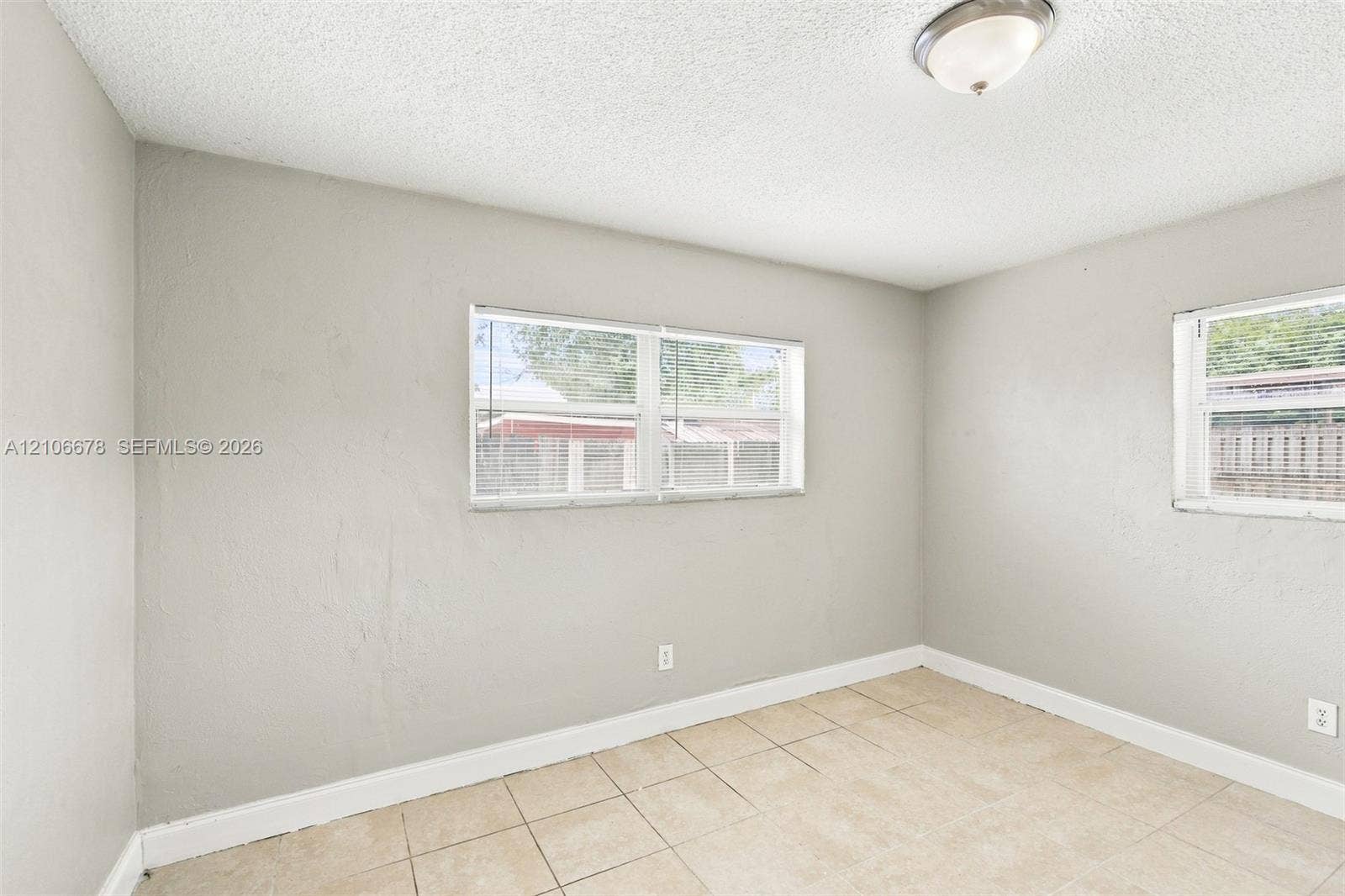 Neutral-toned walls, large windows with integrated blinds, and ceramic tile flooring