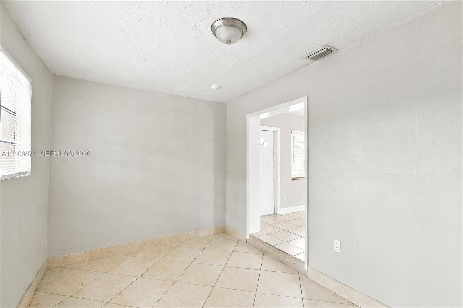 7060 Hood Street, Hollywood, Hollywood, FL 33024 Neutral-toned interior space featuring light-colored diagonal floor tiling, semi-flush mount ceiling lighting, and a window with horizontal blinds