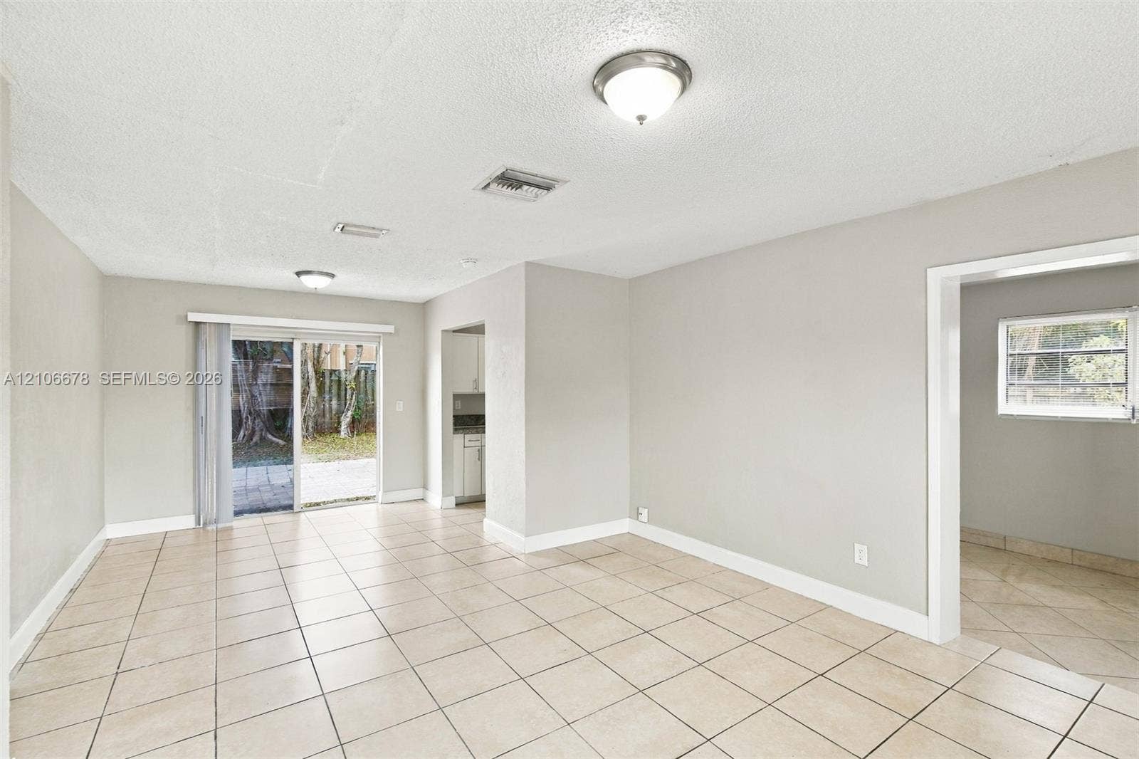 Neutral-toned interior featuring ceramic tile flooring, sliding glass doors, and flush-mount ceiling lighting