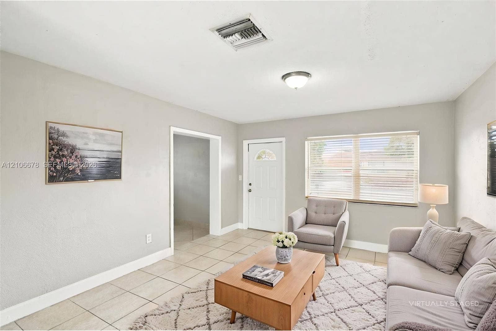 Neutral-toned walls, tile flooring, and a single-light ceiling fixture, complemented by horizontal window blinds and a six-panel entry door