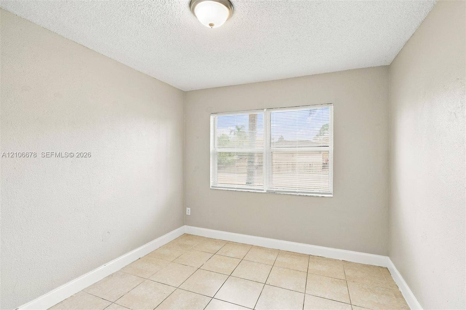Interior room featuring neutral-toned walls, tile flooring, and a flush-mount ceiling light fixture