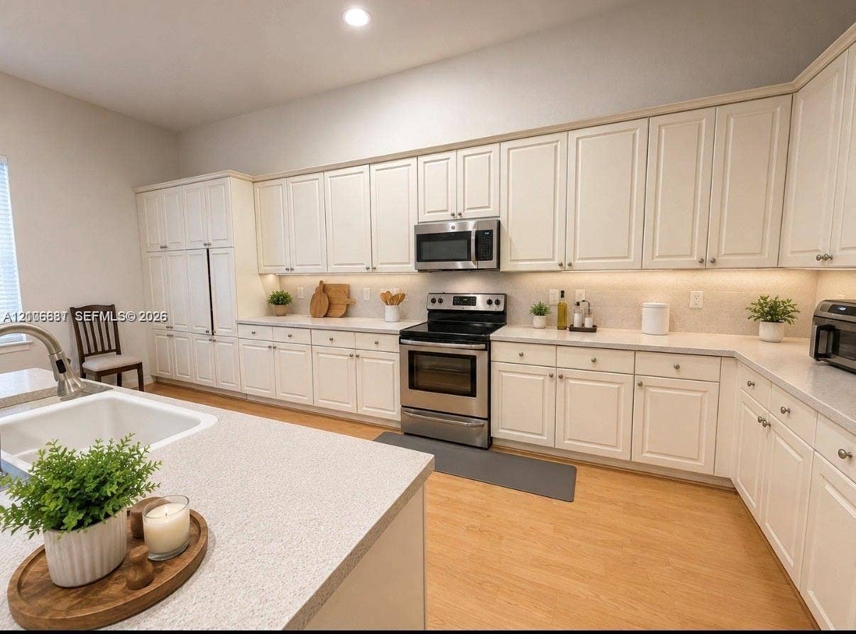 1213 Skylark Drive, #1213, Weston, Weston, FL 33327 Kitchen featuring white cabinetry, solid-surface countertops, stainless steel appliances, and wood-finish flooring