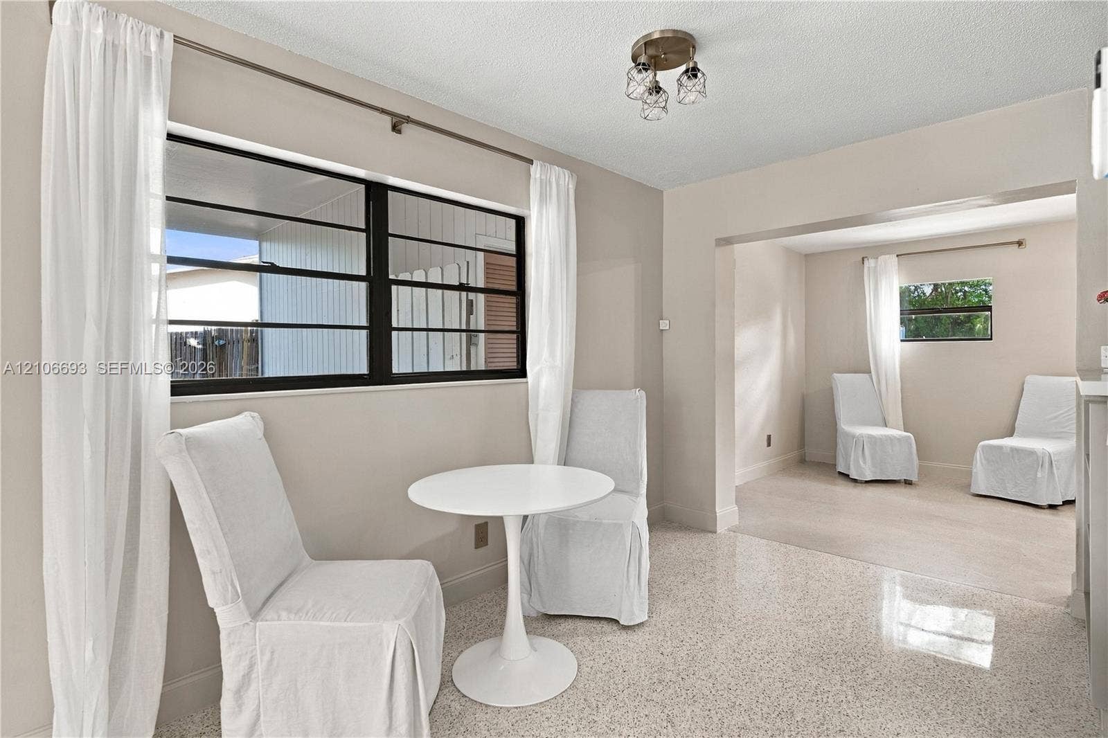 1459 42nd Street, West Palm Beach, FL 33407 Neutral wall finishes, multi-lite horizontal sliding windows with dark framing, polished aggregate flooring, and a three-light semi-flush mount fixture