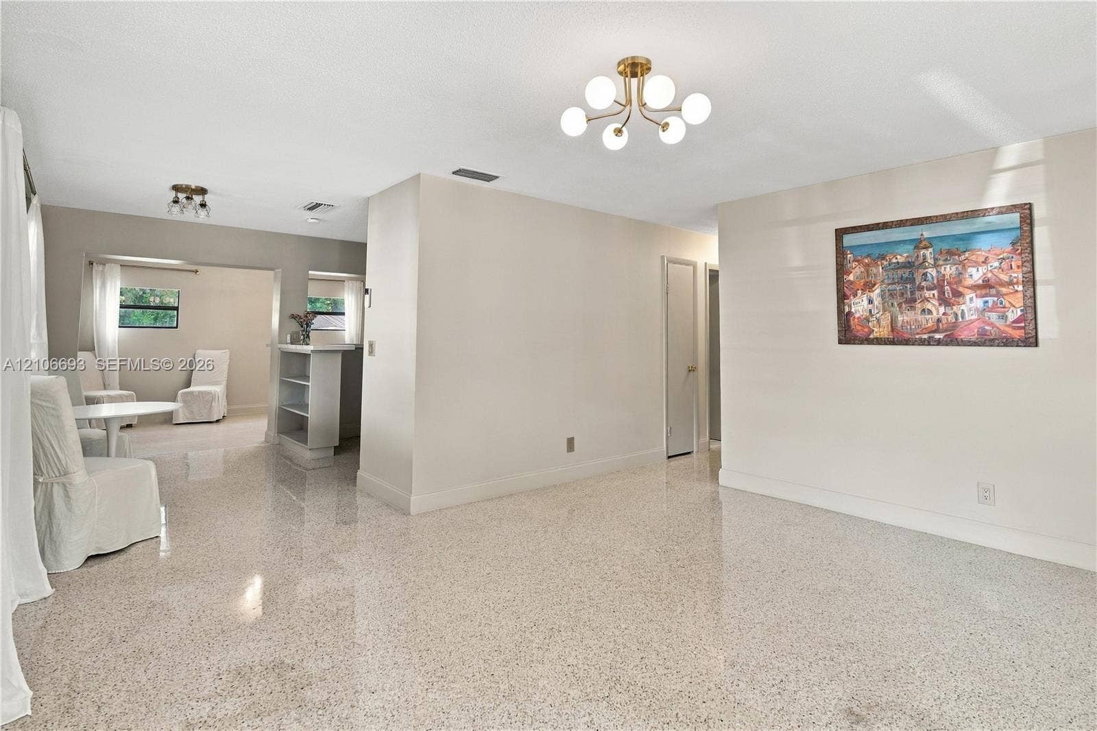 1459 42nd Street, West Palm Beach, FL 33407 Polished stone flooring throughout, multi-arm globe chandeliers, built-in shelving unit, and neutral interior paint