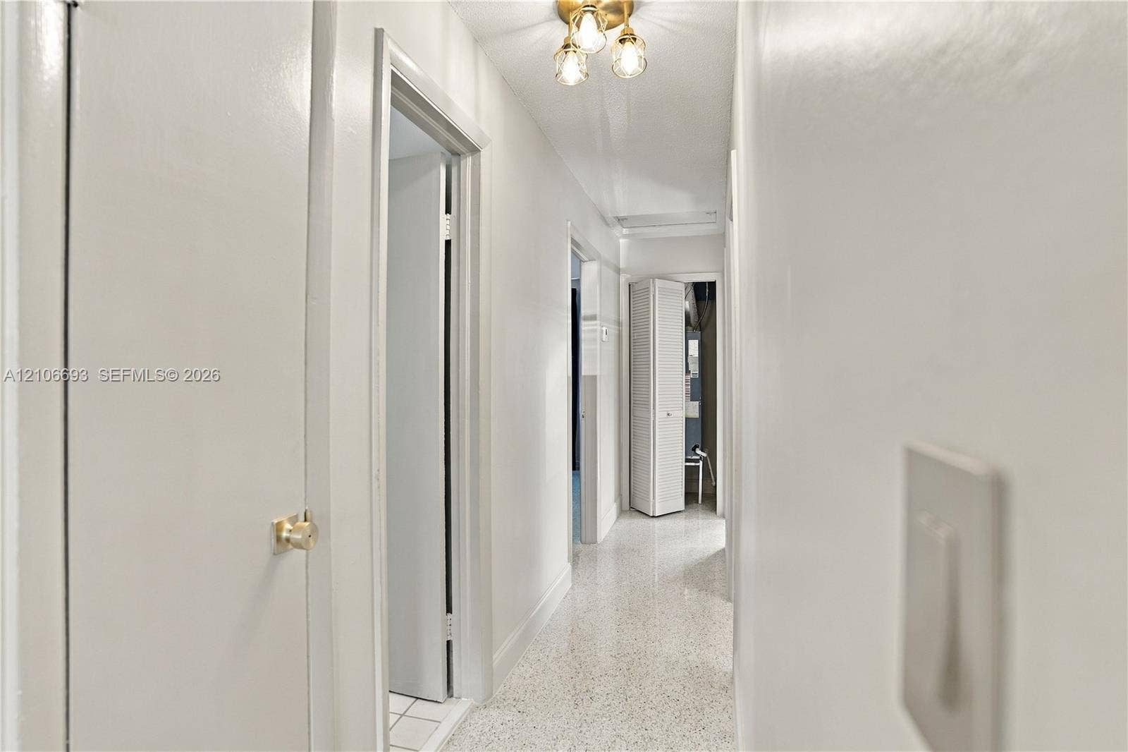 1459 42nd Street, West Palm Beach, FL 33407 Hallway featuring neutral wall finishes, terrazzo flooring, and a multi-bulb ceiling-mounted light fixture