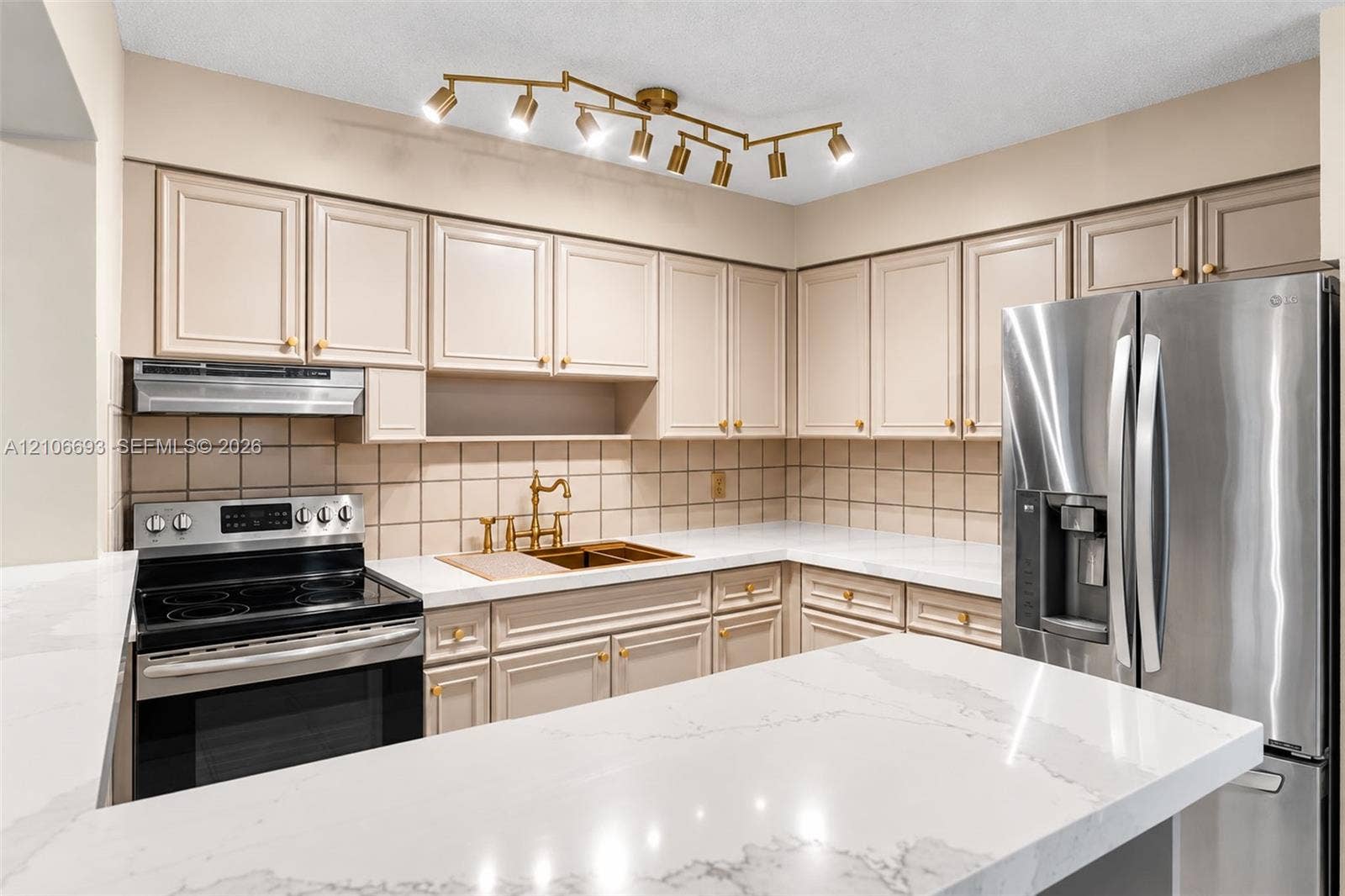 1459 42nd Street, West Palm Beach, FL 33407 Kitchen featuring quartz countertops, shaker-style cabinetry, a multi-light directional ceiling fixture, stainless steel appliances, and a tiled backsplash
