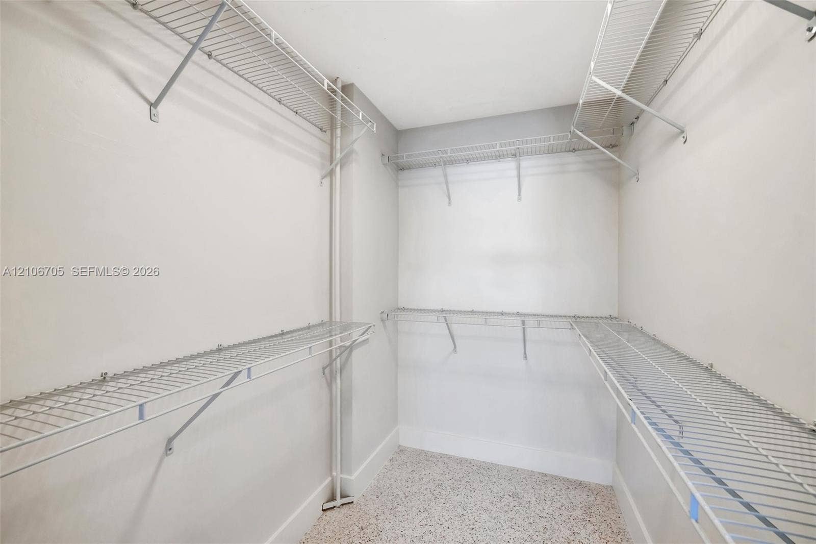 Storage area featuring multi-level white wire shelving and neutral flooring