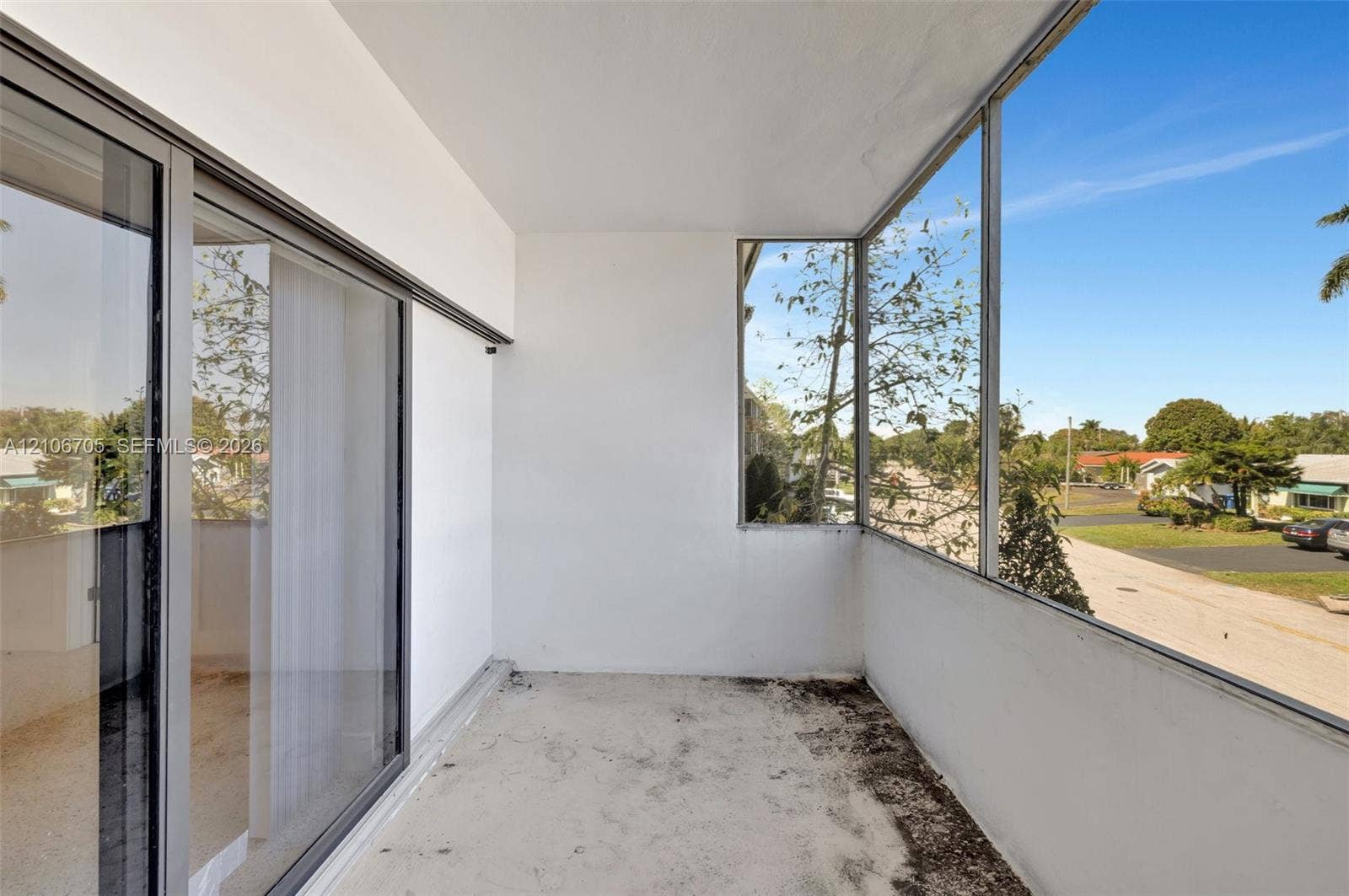 Enclosed balcony featuring floor-to-ceiling glass paneling and sliding glass door entry