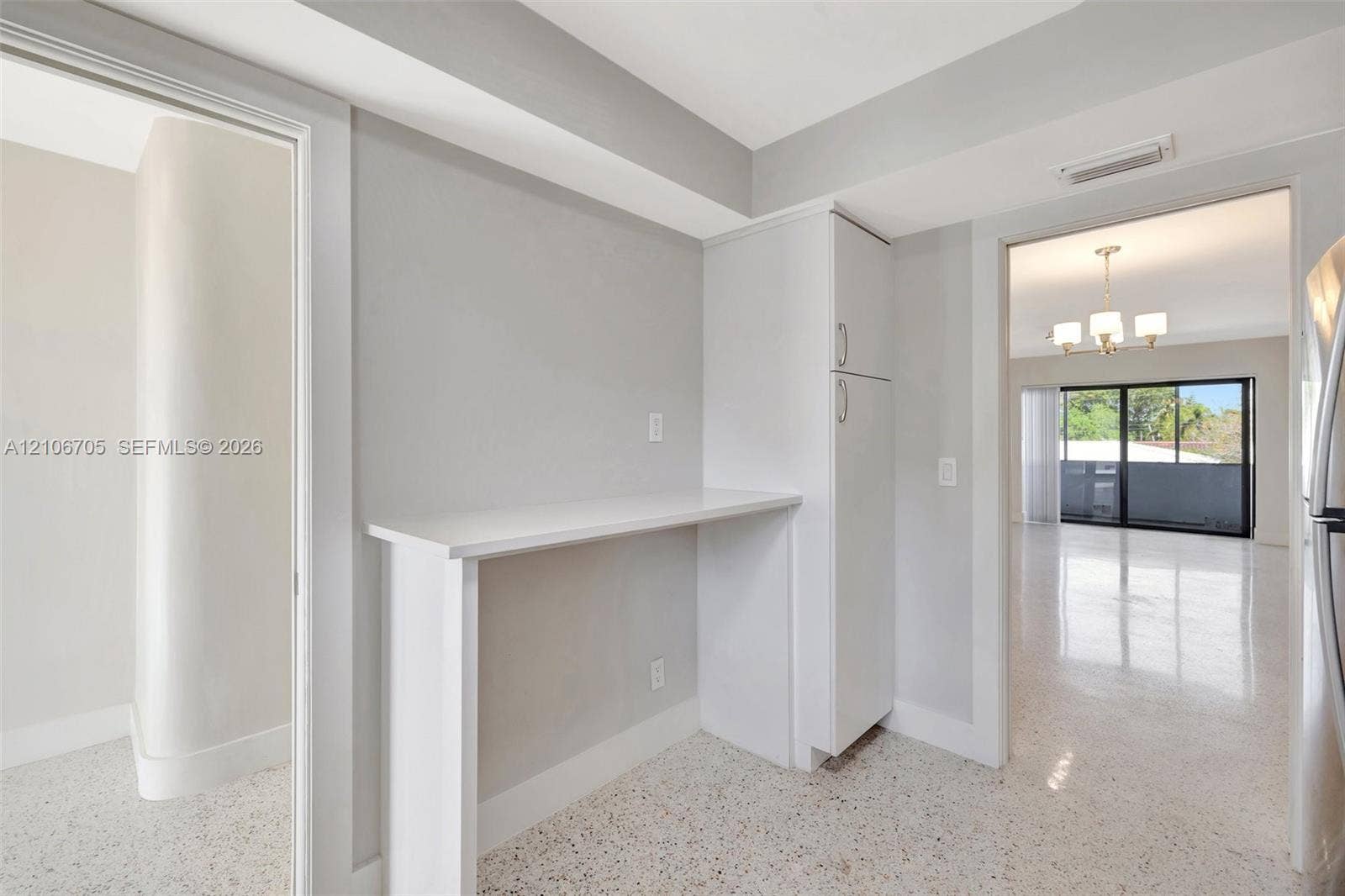 Built-in white cabinetry, countertop nook, polished terrazzo flooring, and recessed ceiling lighting