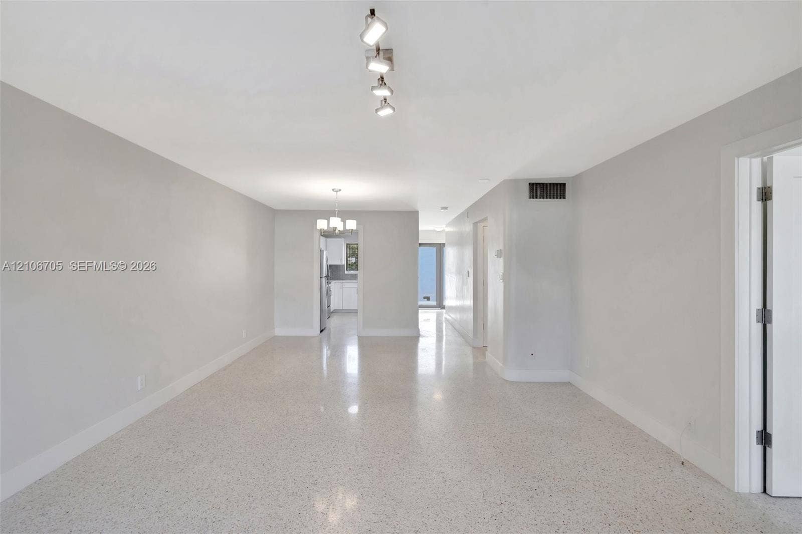 Open-concept interior featuring light-toned interior paint, polished terrazzo flooring, and a multi-directional track lighting fixture