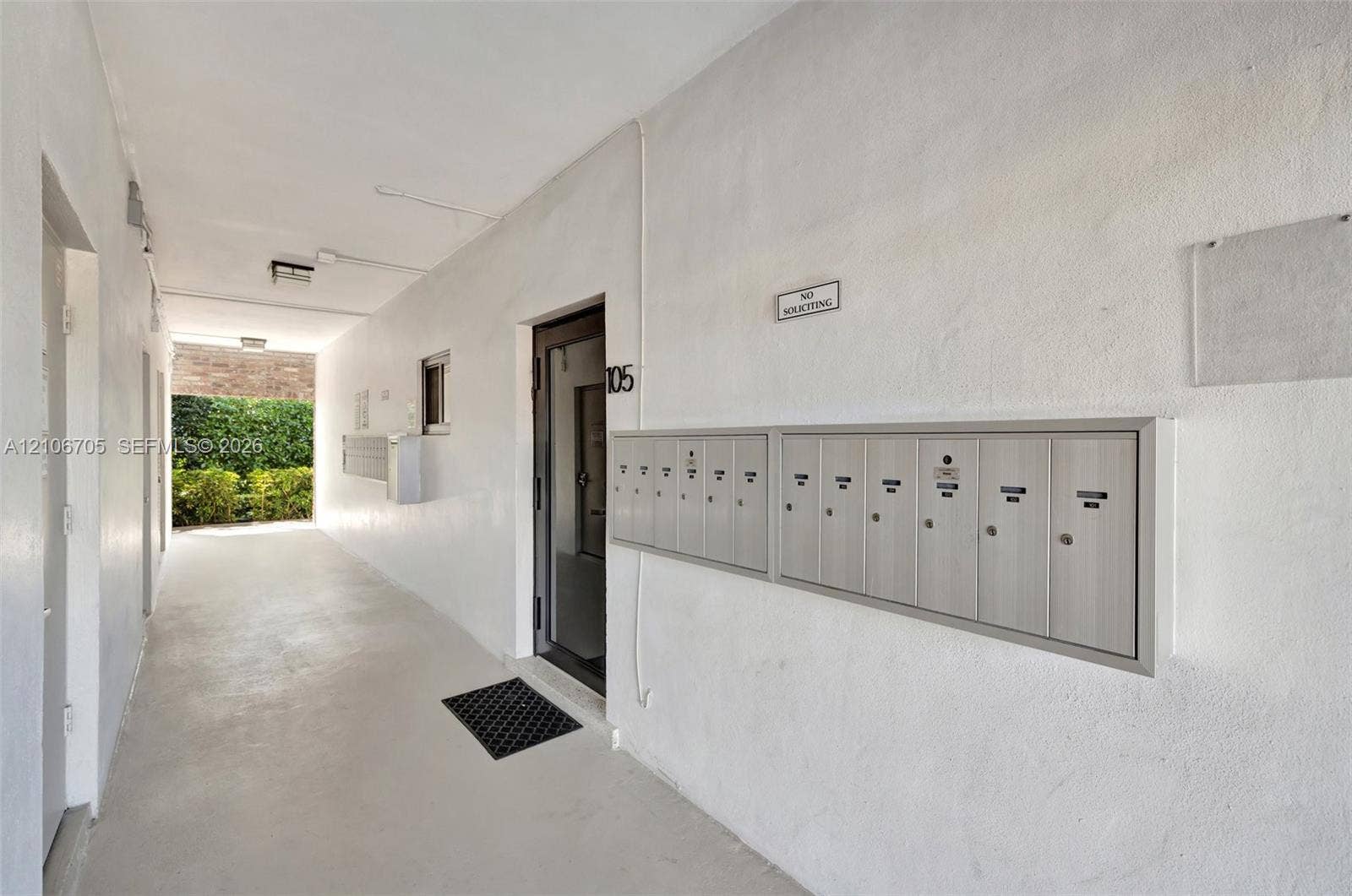 Covered walkway featuring a bank of recessed metal mailboxes and textured wall surfaces