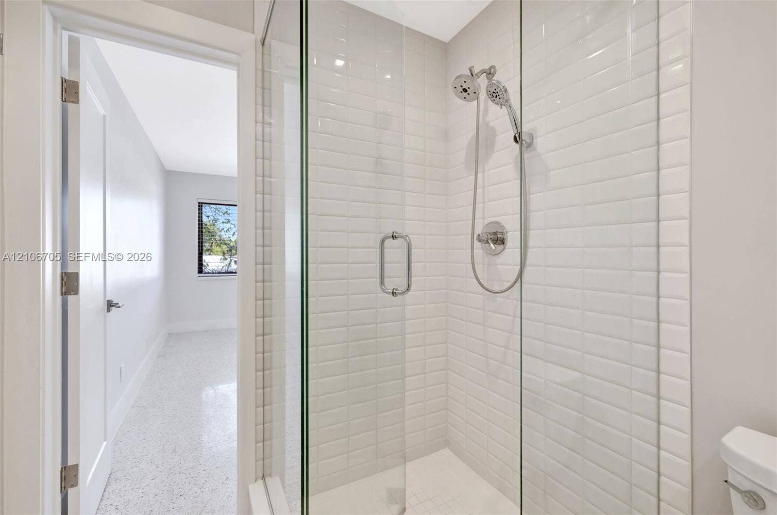 Walk-in shower featuring glass panel enclosure, white subway tile wall surround, and dual-function shower head with handheld attachment
