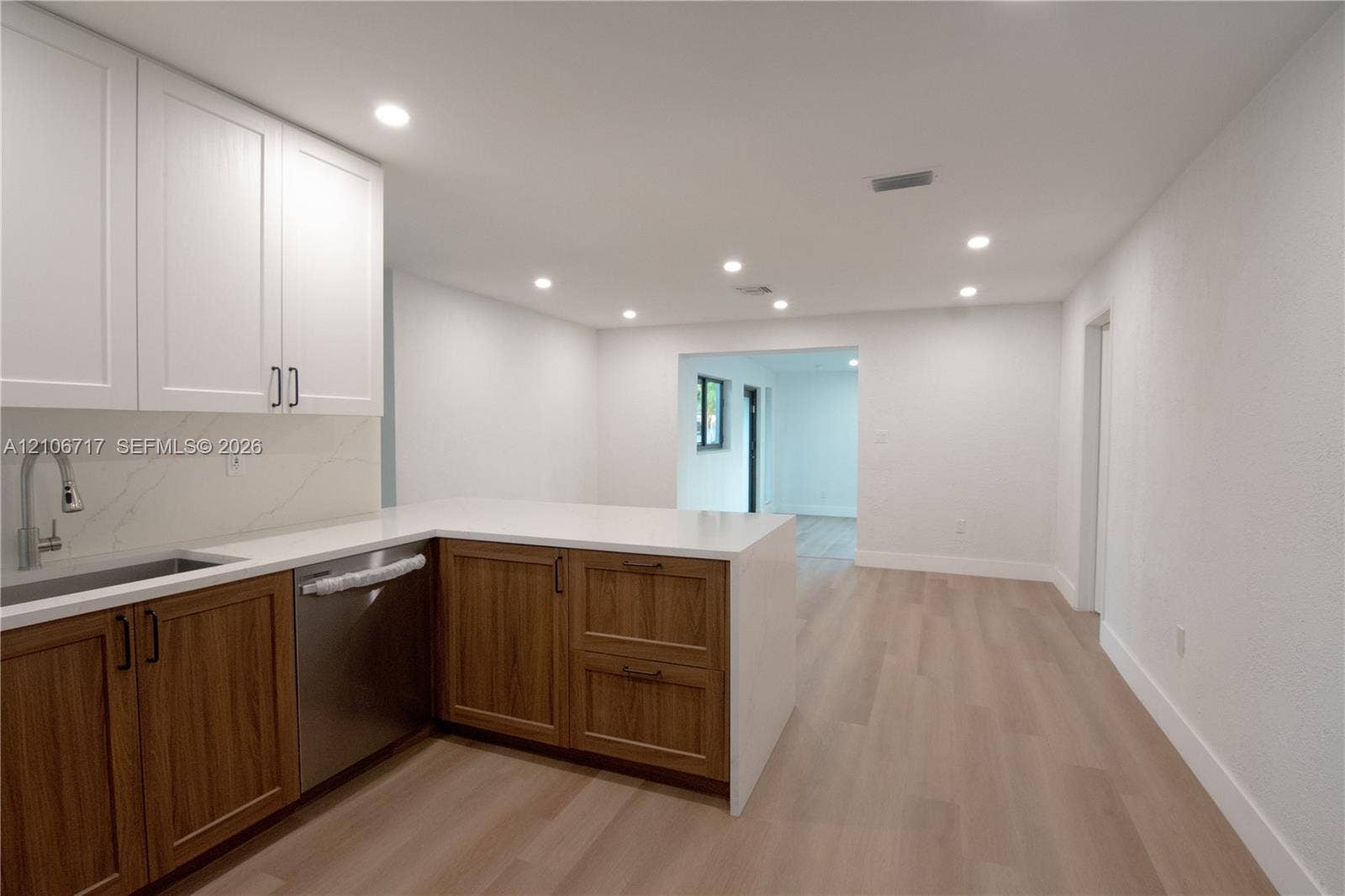 6811 Thomas Street, Hollywood, FL 33024 Kitchen featuring dual-tone shaker cabinetry, quartz countertops, stainless steel undermount sink with gooseneck faucet, integrated stainless steel dishwasher, and wood-finish flooring