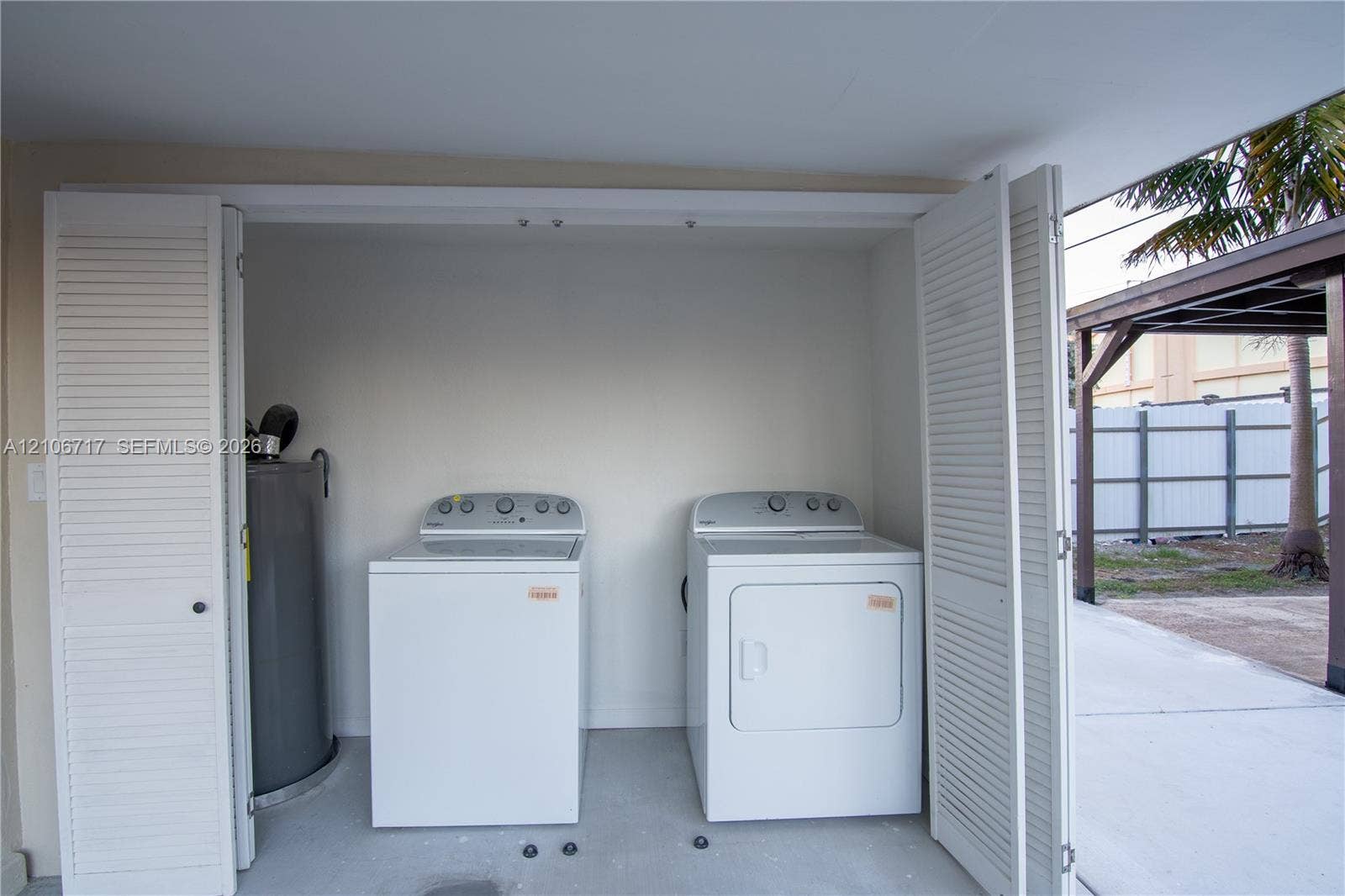 6811 Thomas Street, Hollywood, FL 33024 Laundry area featuring bi-fold louvered doors, white appliances, and a cylindrical water heater