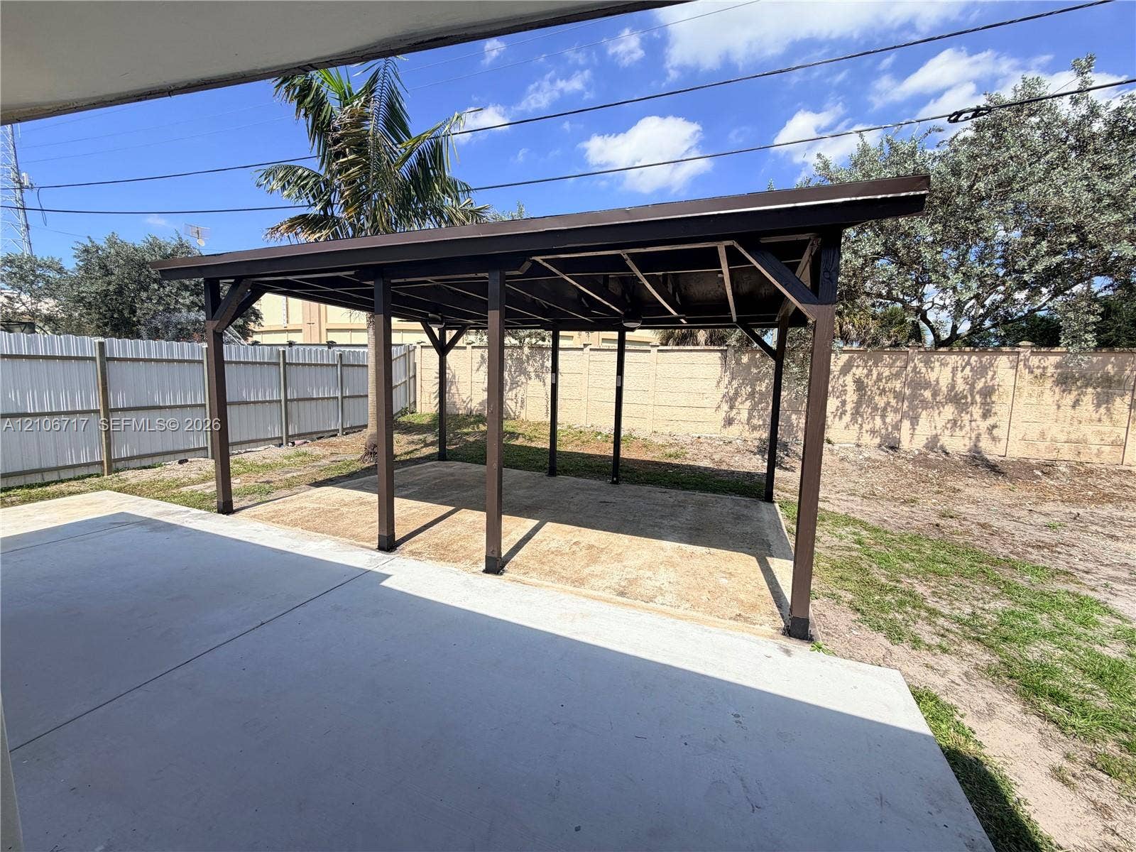 6811 Thomas Street, Hollywood, FL 33024 Covered carport featuring a structural timber frame, concrete slab, and privacy fencing