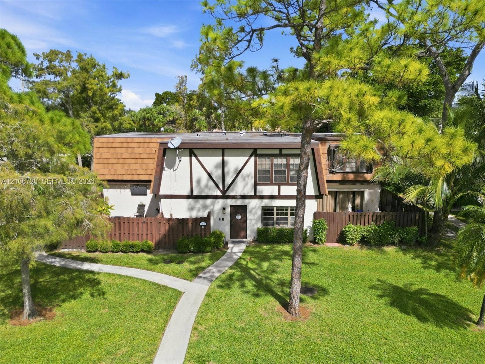 152 Weybridge Circle, #C, Royal Palm Beach, FL 33411 Mansard-style exterior featuring half-timbered detailing, a paved walkway, and an enclosed privacy fence