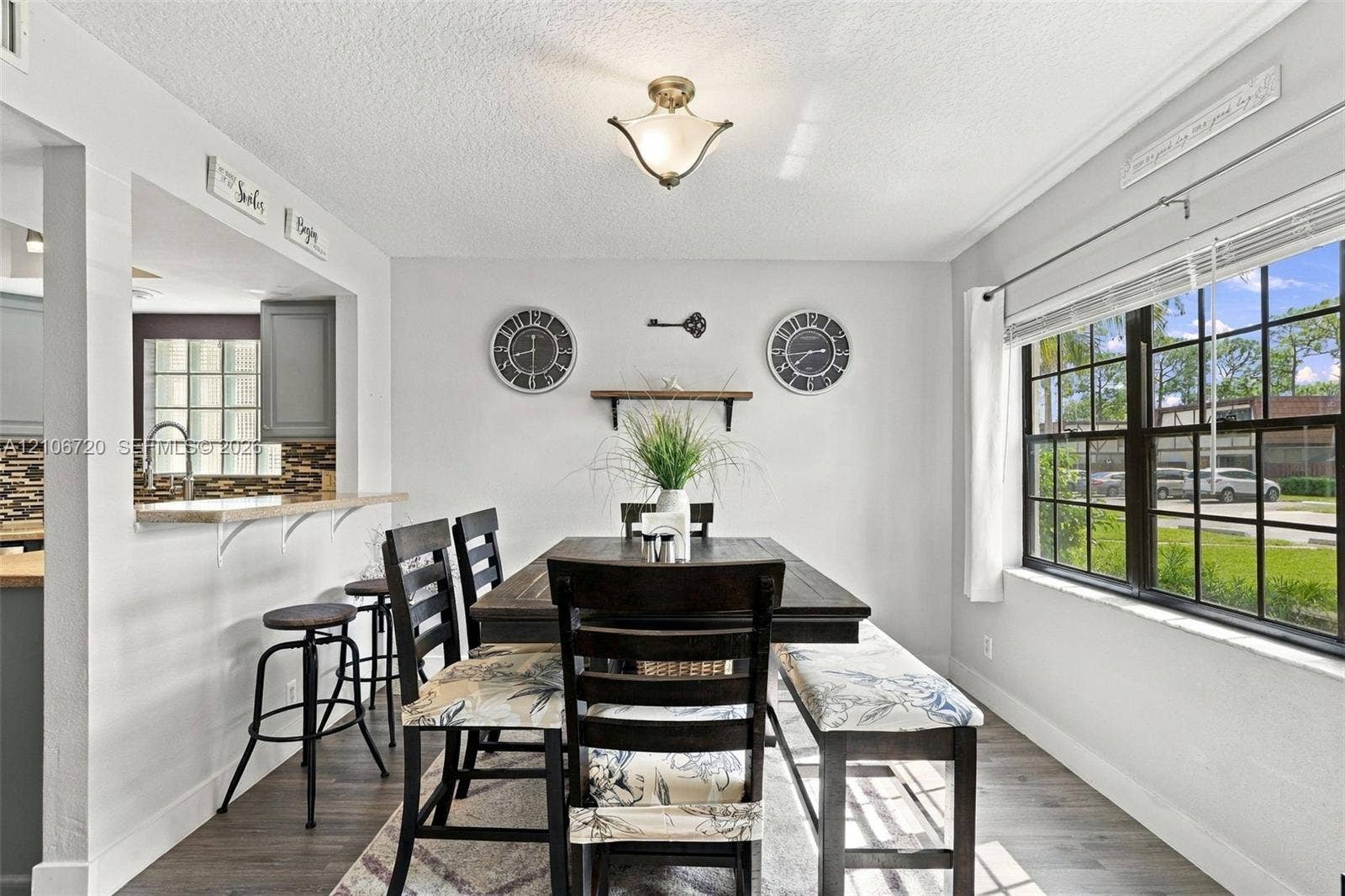 152 Weybridge Circle, #C, Royal Palm Beach, FL 33411 Dining area featuring wood-finish flooring, a pass-through window with a breakfast bar, and a multi-pane window with natural lighting
