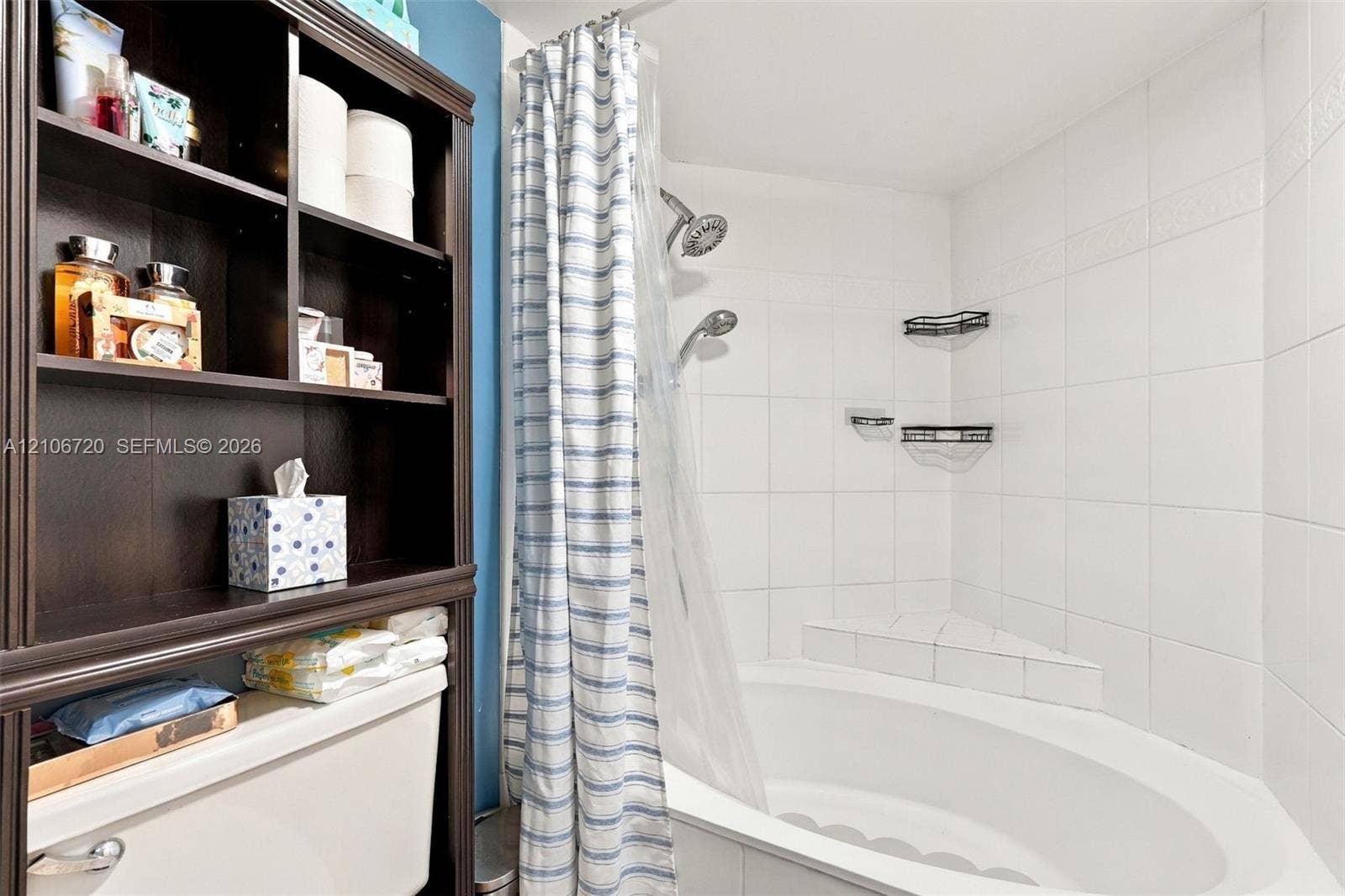 152 Weybridge Circle, #C, Royal Palm Beach, FL 33411 Built-in floor-to-ceiling shelving, soaking tub with integrated corner seating, and white tile tub surround featuring dual shower heads and metal wall-mounted storage racks