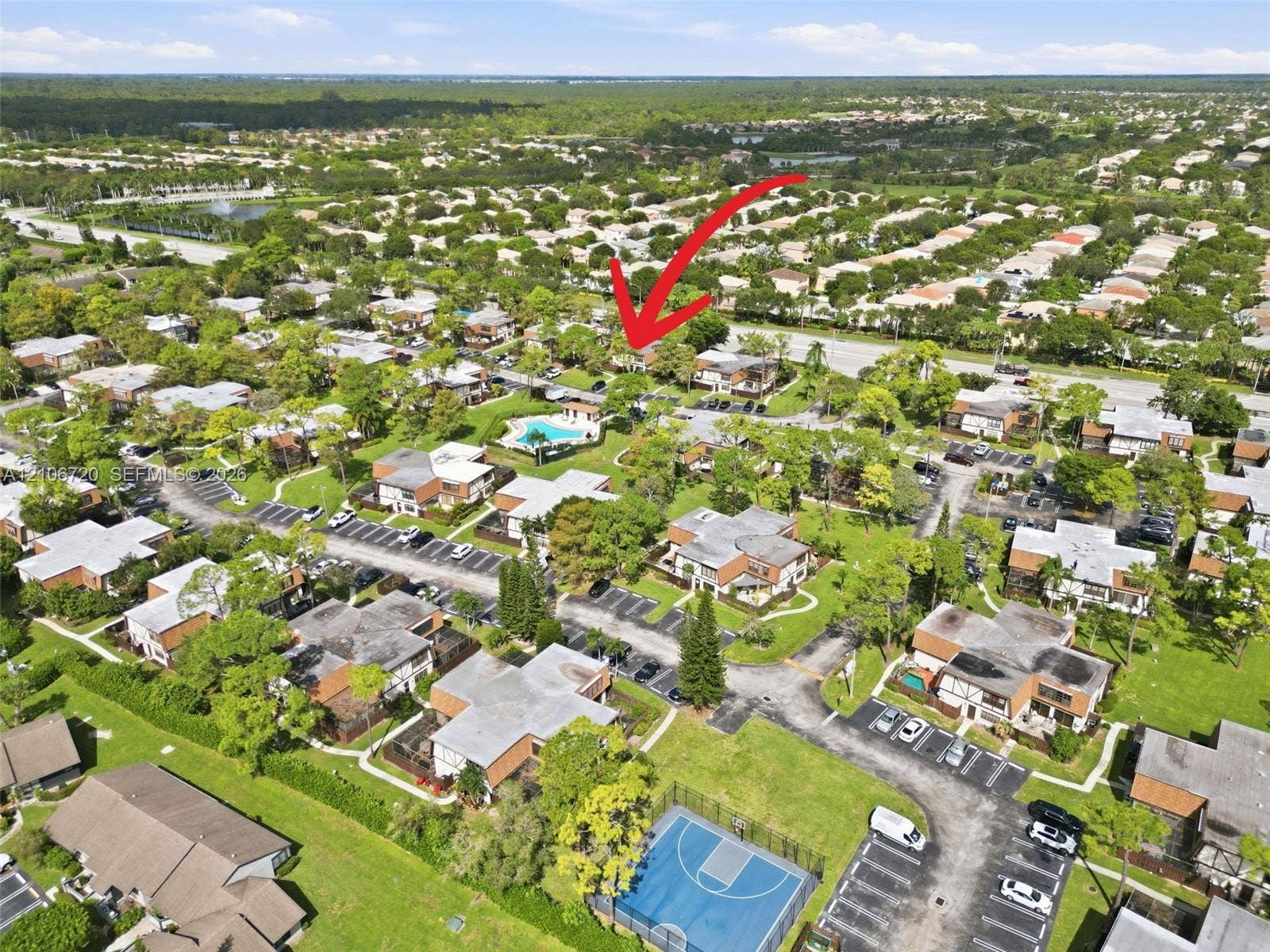 152 Weybridge Circle, #C, Royal Palm Beach, FL 33411 Aerial perspective of residential community featuring a swimming pool, basketball court, paved parking areas, and mature landscaping