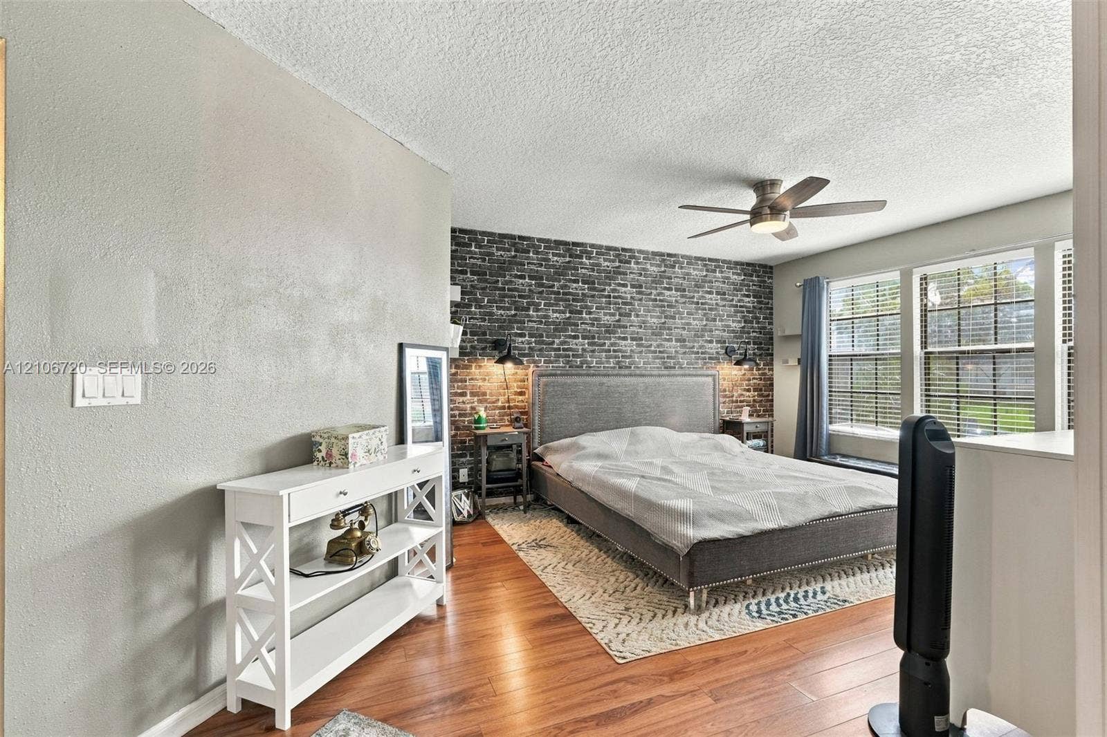152 Weybridge Circle, #C, Royal Palm Beach, FL 33411 Bedroom featuring wood-finish flooring, a textured accent wall, integrated wall-mounted lighting, and a ceiling fan