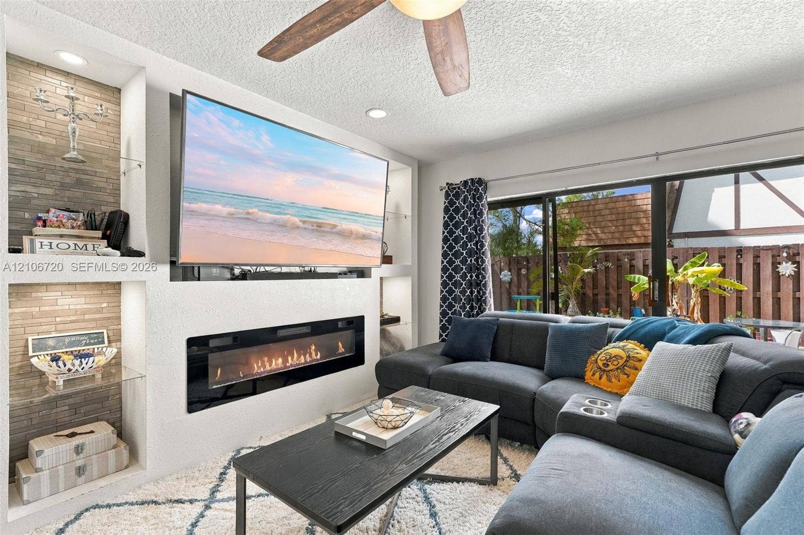 152 Weybridge Circle, #C, Royal Palm Beach, FL 33411 Built-in wall cabinetry with recessed lighting, stone-tiled accent shelving, linear electric fireplace, and sliding glass patio doors