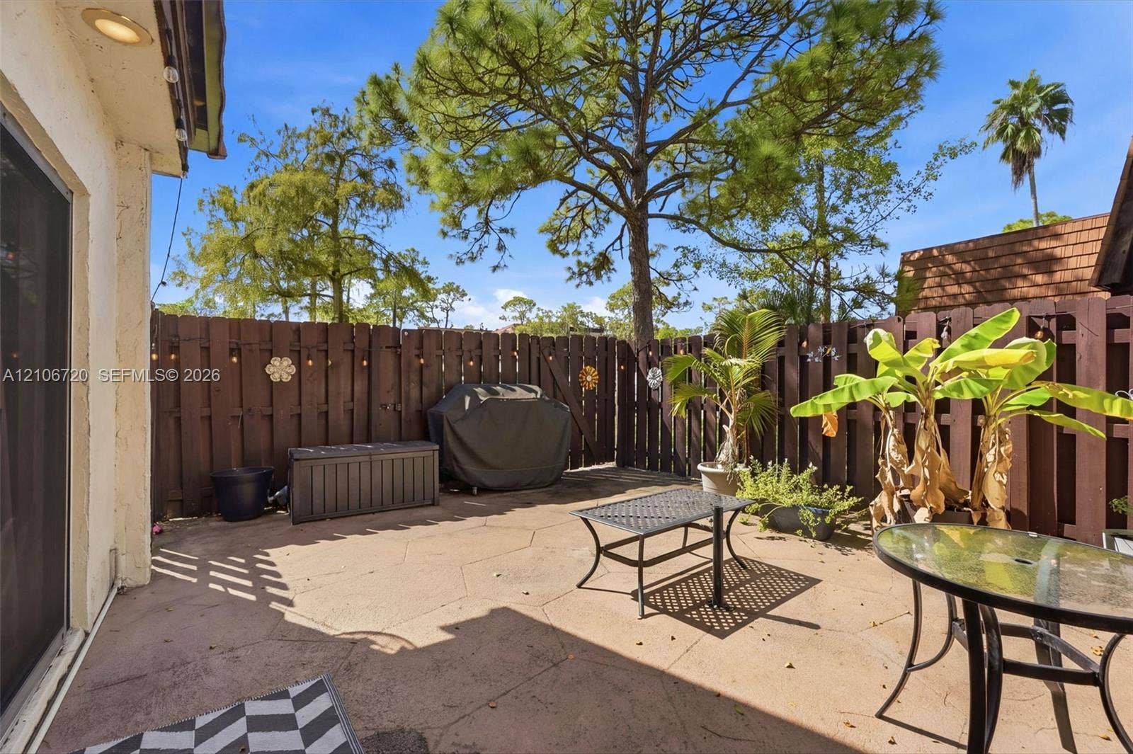 152 Weybridge Circle, #C, Royal Palm Beach, FL 33411 Private patio featuring a concrete paver surface, enclosed by a solid wood privacy fence and mature landscaping