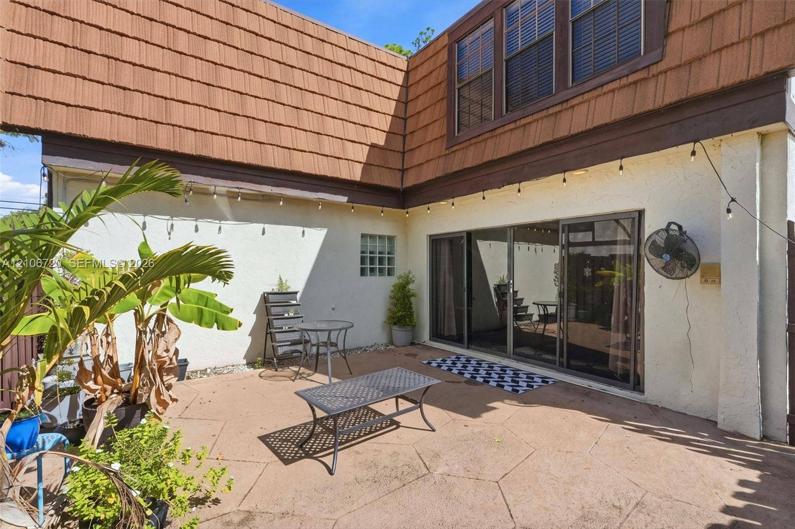 152 Weybridge Circle, #C, Royal Palm Beach, FL 33411 Concrete paver patio featuring stucco exterior walls, sliding glass doors, glass block accent window, and brown shake siding