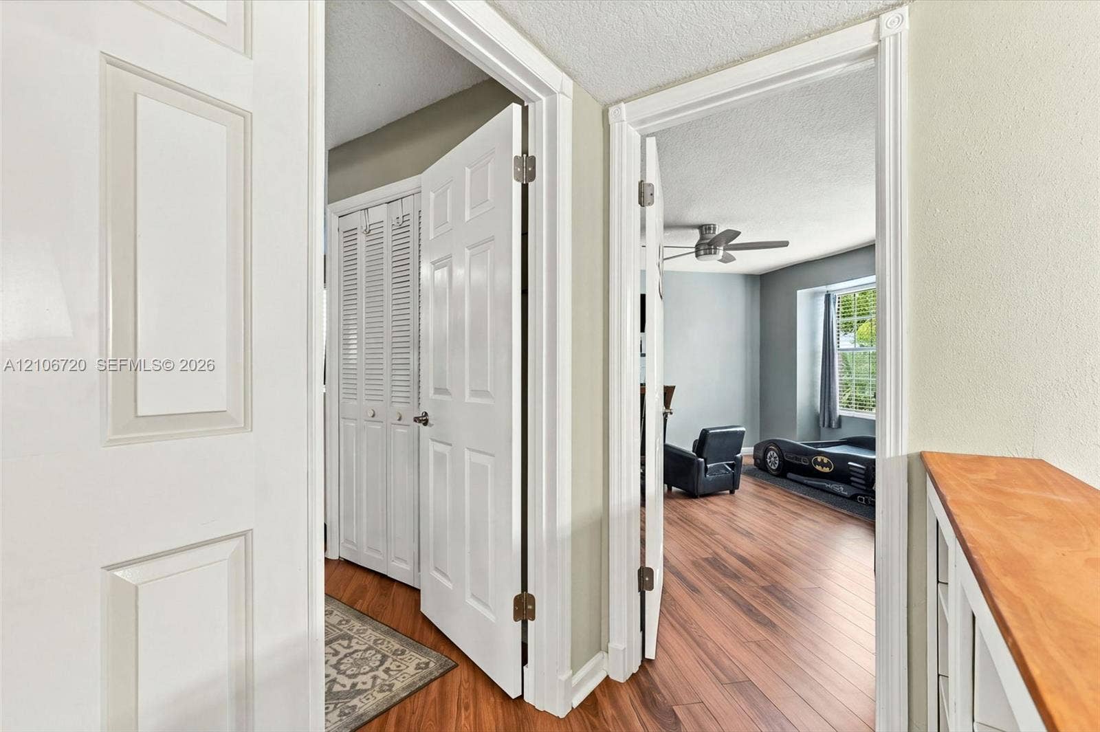 152 Weybridge Circle, #C, Royal Palm Beach, FL 33411 Interior space featuring wood-finish flooring, white paneled doors, louvered bi-fold closet doors, a built-in wooden shelving unit, and a ceiling fan