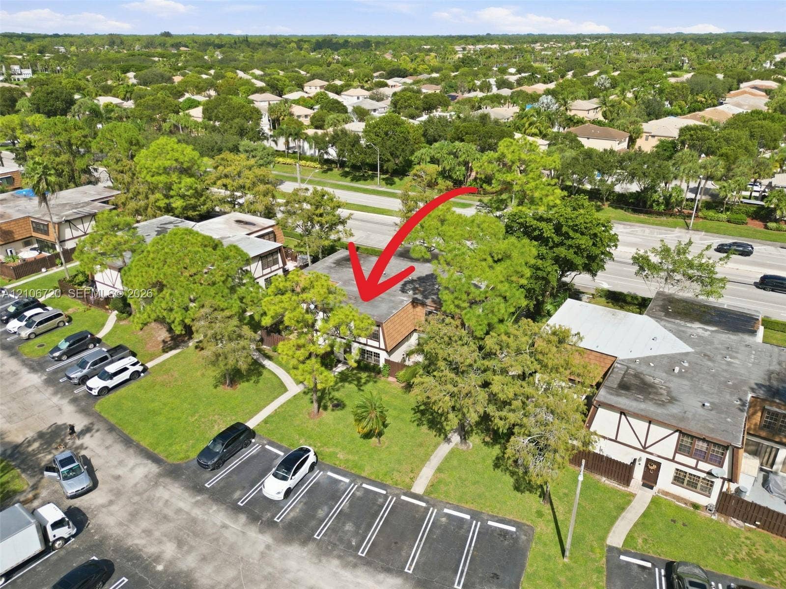 152 Weybridge Circle, #C, Royal Palm Beach, FL 33411 Aerial perspective of a multi-unit complex featuring shingled rooflines, exterior timber-frame detailing, established shade trees, and dedicated asphalt parking areas