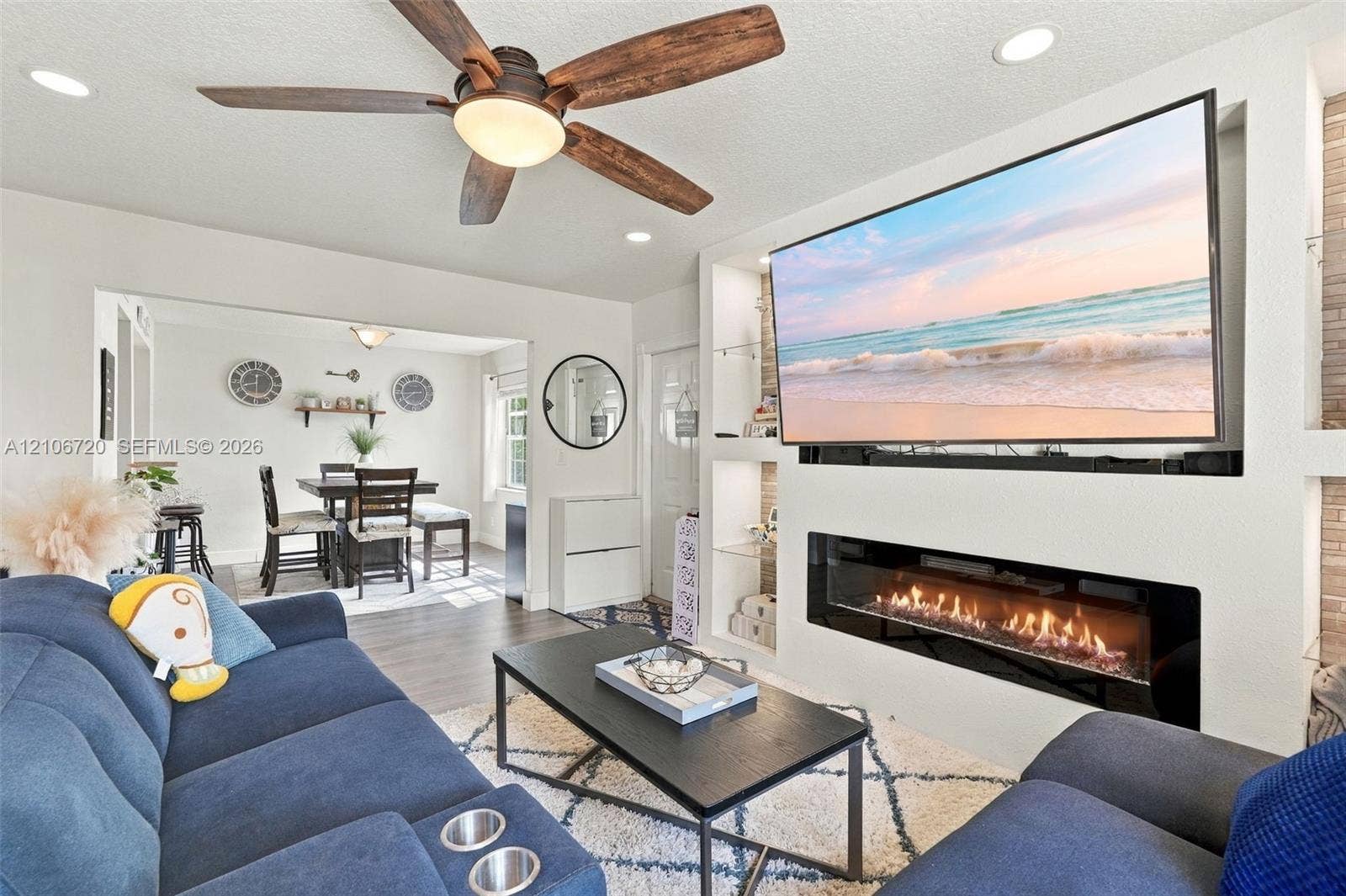 152 Weybridge Circle, #C, Royal Palm Beach, FL 33411 Built-in media wall featuring a linear electric fireplace, recessed shelving with glass inserts, recessed lighting, and a multi-blade ceiling fan