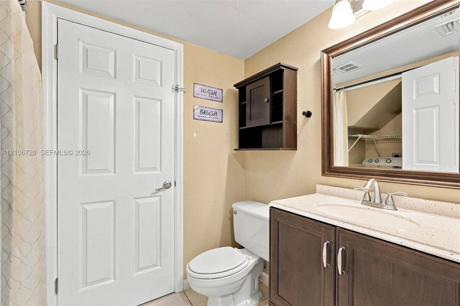 152 Weybridge Circle, #C, Royal Palm Beach, FL 33411 Bathroom featuring a vanity with a light-toned solid surface countertop, an oval undermount sink, a framed wall mirror, and dark-finish built-in cabinetry