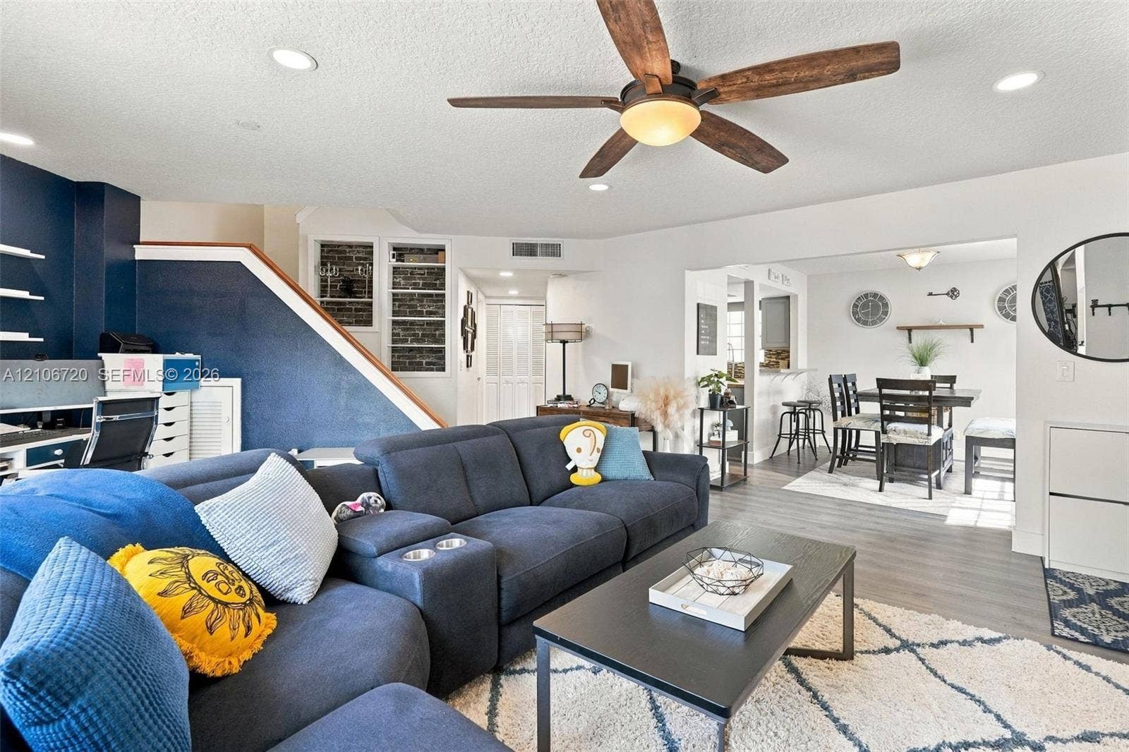 152 Weybridge Circle, #C, Royal Palm Beach, FL 33411 Open-concept living space featuring wood-finish flooring, recessed lighting, a ceiling fan with integrated lighting, and an accent wall with exposed brick detailing
