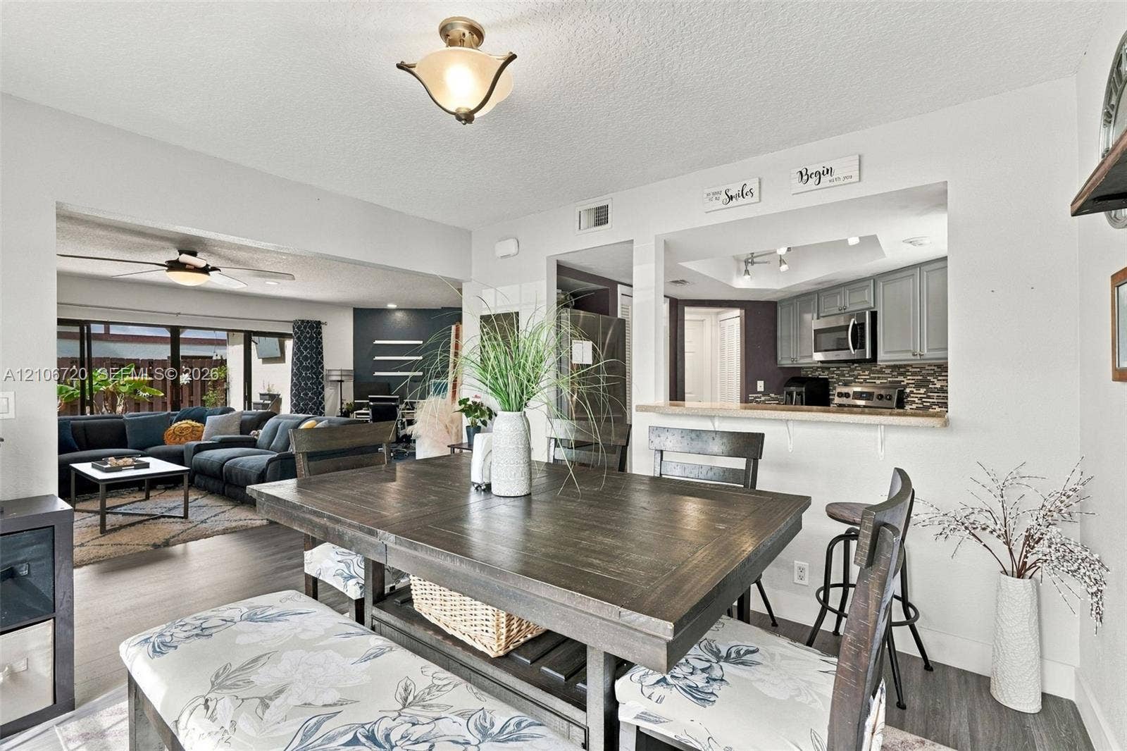 152 Weybridge Circle, #C, Royal Palm Beach, FL 33411 Dining area featuring wood-finish flooring, a pass-through opening to the kitchen, and a flush-mount light fixture