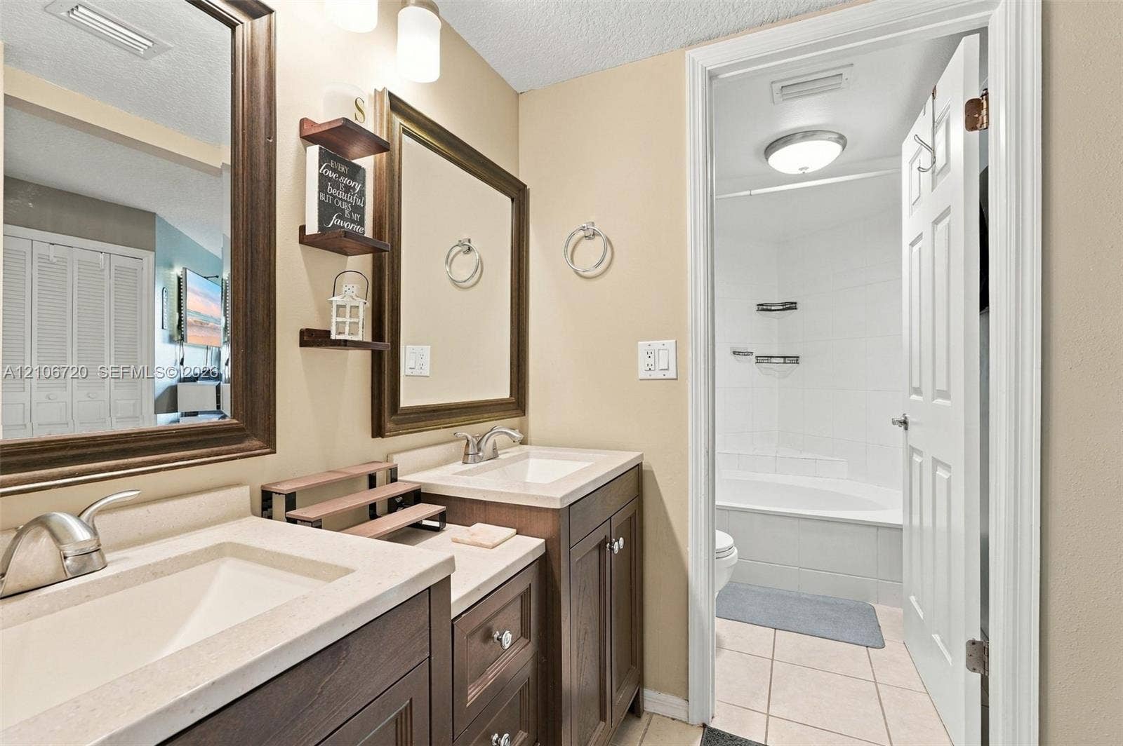 152 Weybridge Circle, #C, Royal Palm Beach, FL 33411 Double vanity with quartz countertops, integrated rectangular sinks, wood-finish cabinetry, framed mirrors, and a tile-surround bathtub